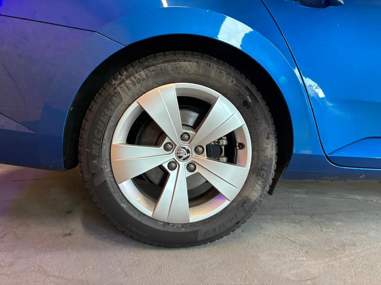 Gros plan sur la roue arrière droite d'une Skoda Superb Combi bleu 2021 avec jante alliage cinq branches.