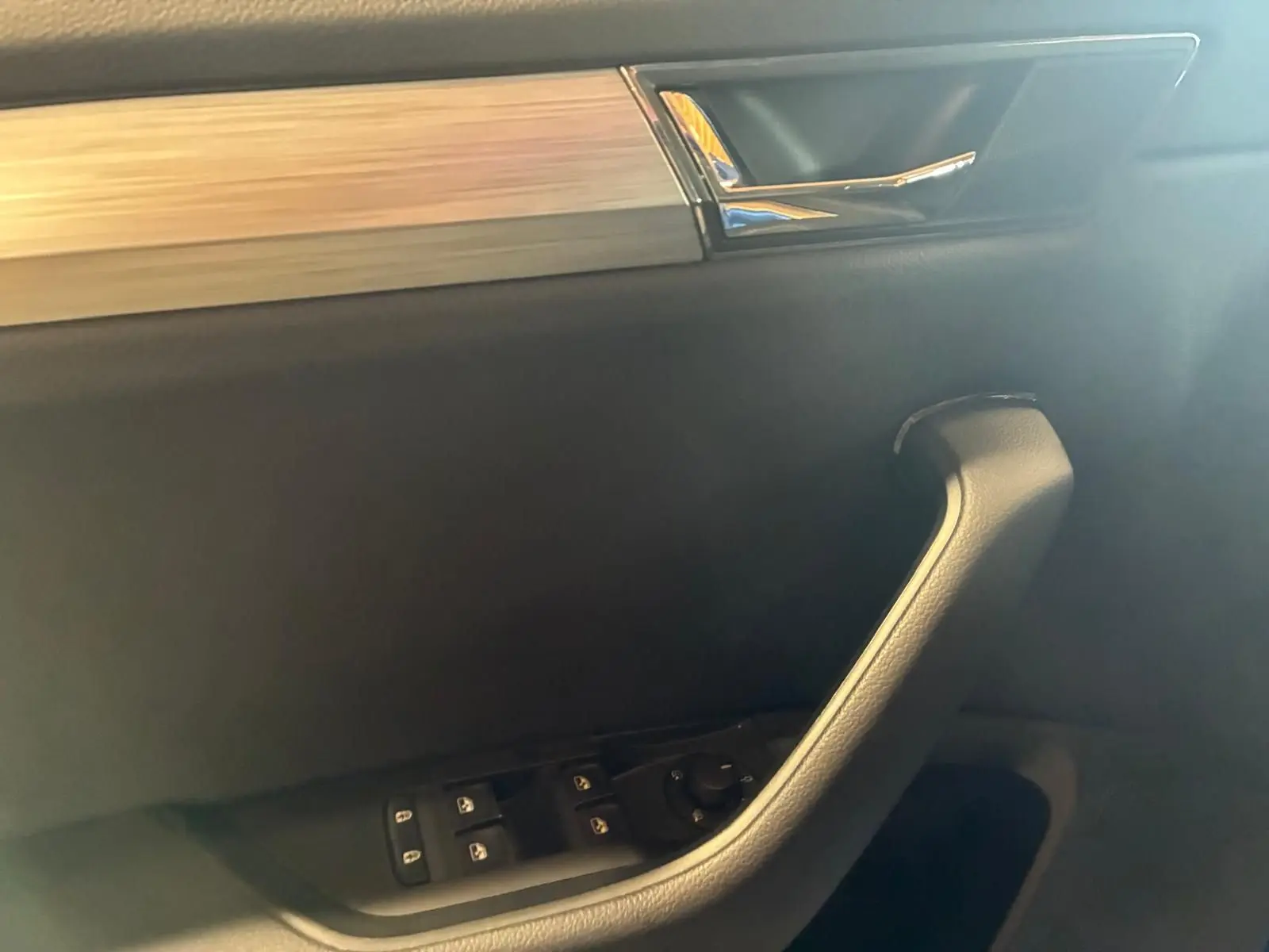 Poignée de porte intérieure côté conducteur de Skoda Superb Combi 2021, avec commande des vitres et insert décoratif chromé.