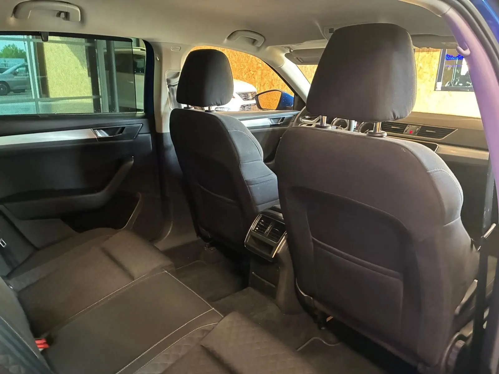 Vue intérieure arrière de la Skoda Superb Combi 2021, sièges tissu noirs et aérateurs centraux visibles.