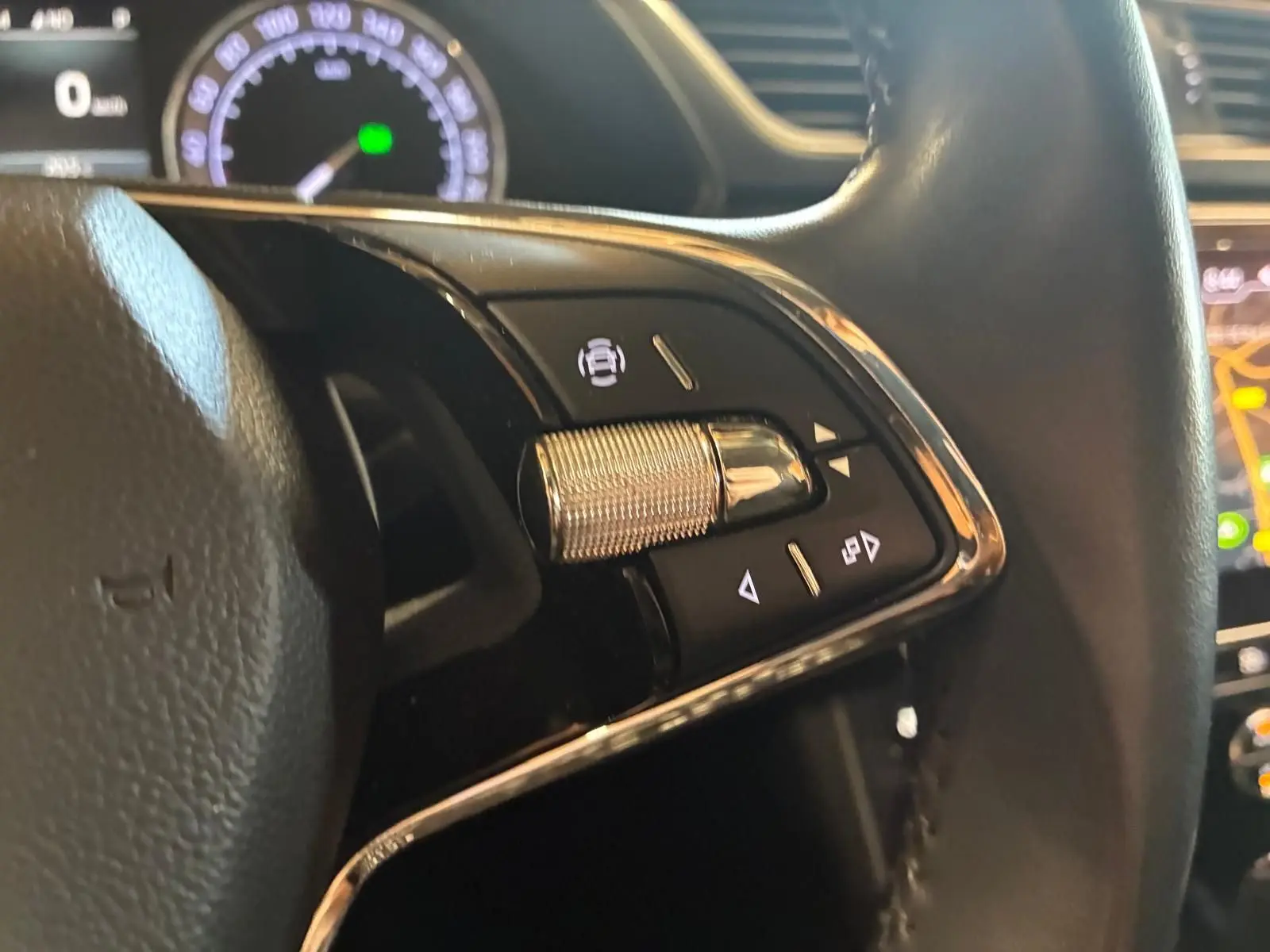 Gros plan sur les commandes à droite du volant noir d'une Skoda Superb Combi 2021, avec tableau de bord et écran en arrière-plan.
