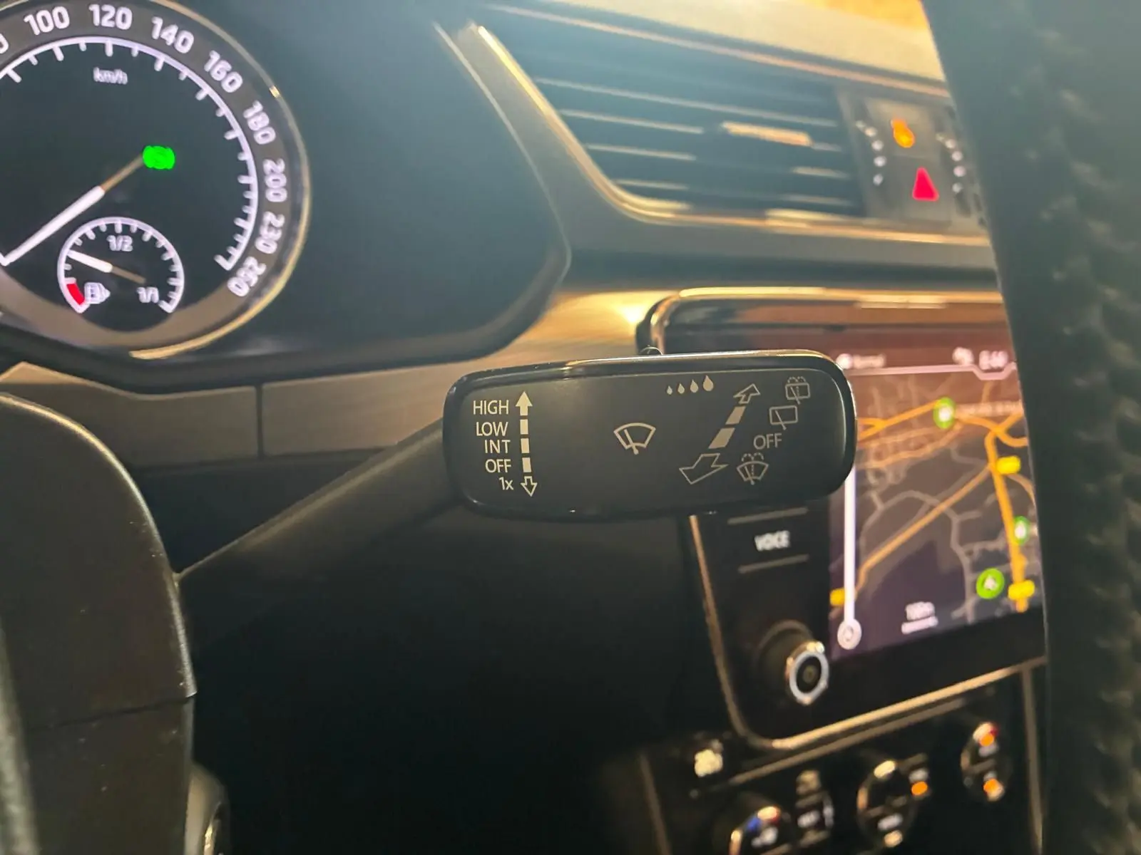Gros plan sur la commande d’essuie-glace côté droit du tableau de bord d’une Skoda Superb Combi bleu, avec écran GPS en arrière-plan.