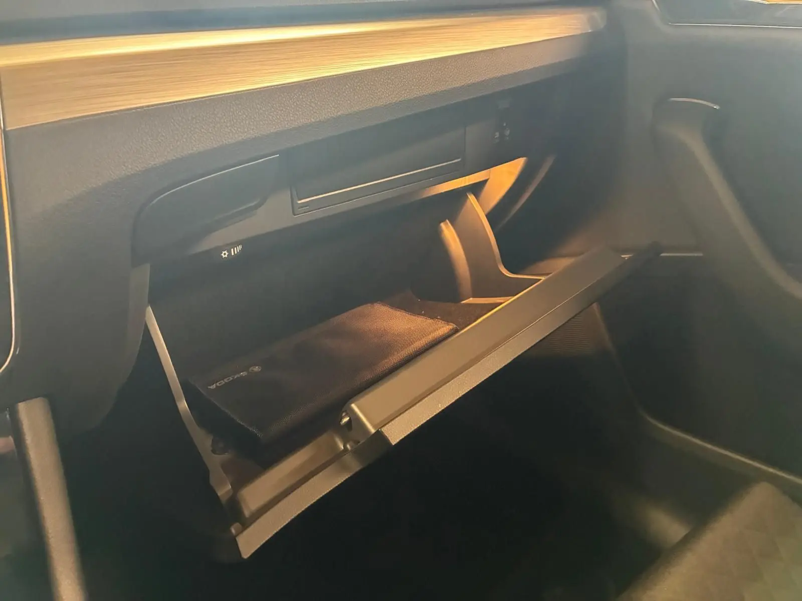 Gros plan sur la boîte à gants ouverte côté passager de la Skoda Superb Combi 2021 avec intérieur noir et rangement visible.