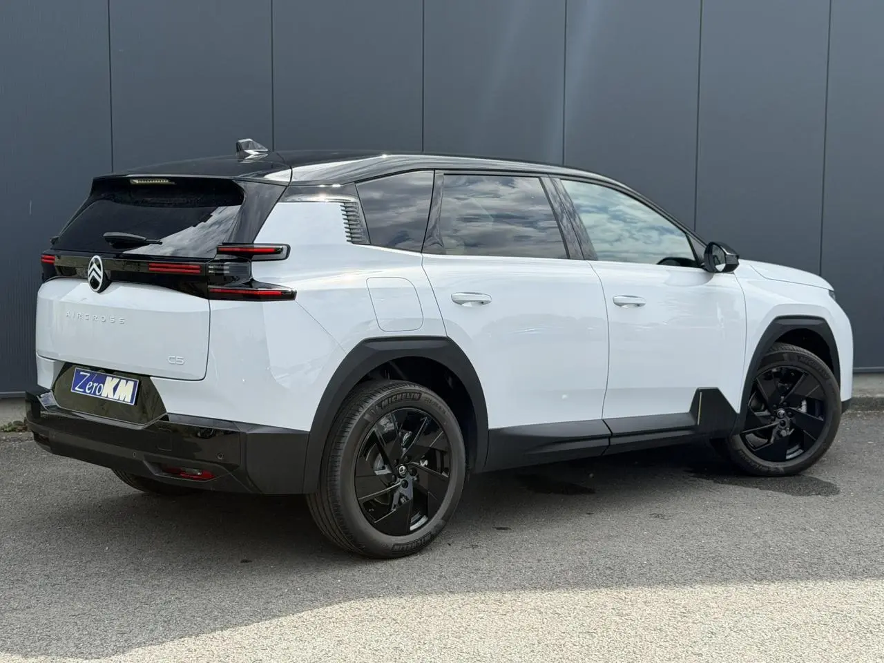 Vue 3/4 arrière droite d'un Citroën C5 Aircross blanc Okenite avec toit noir et jantes alliage noires.