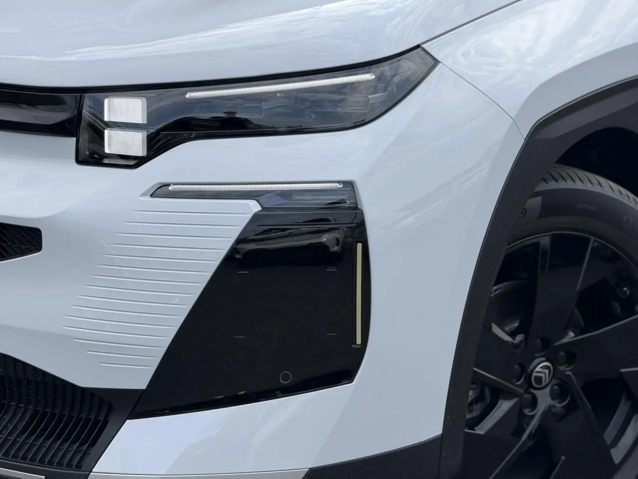 Gros plan sur l'avant droit blanc Okenite du Citroën C5 Aircross avec détails noirs et jante alliage 19 pouces.