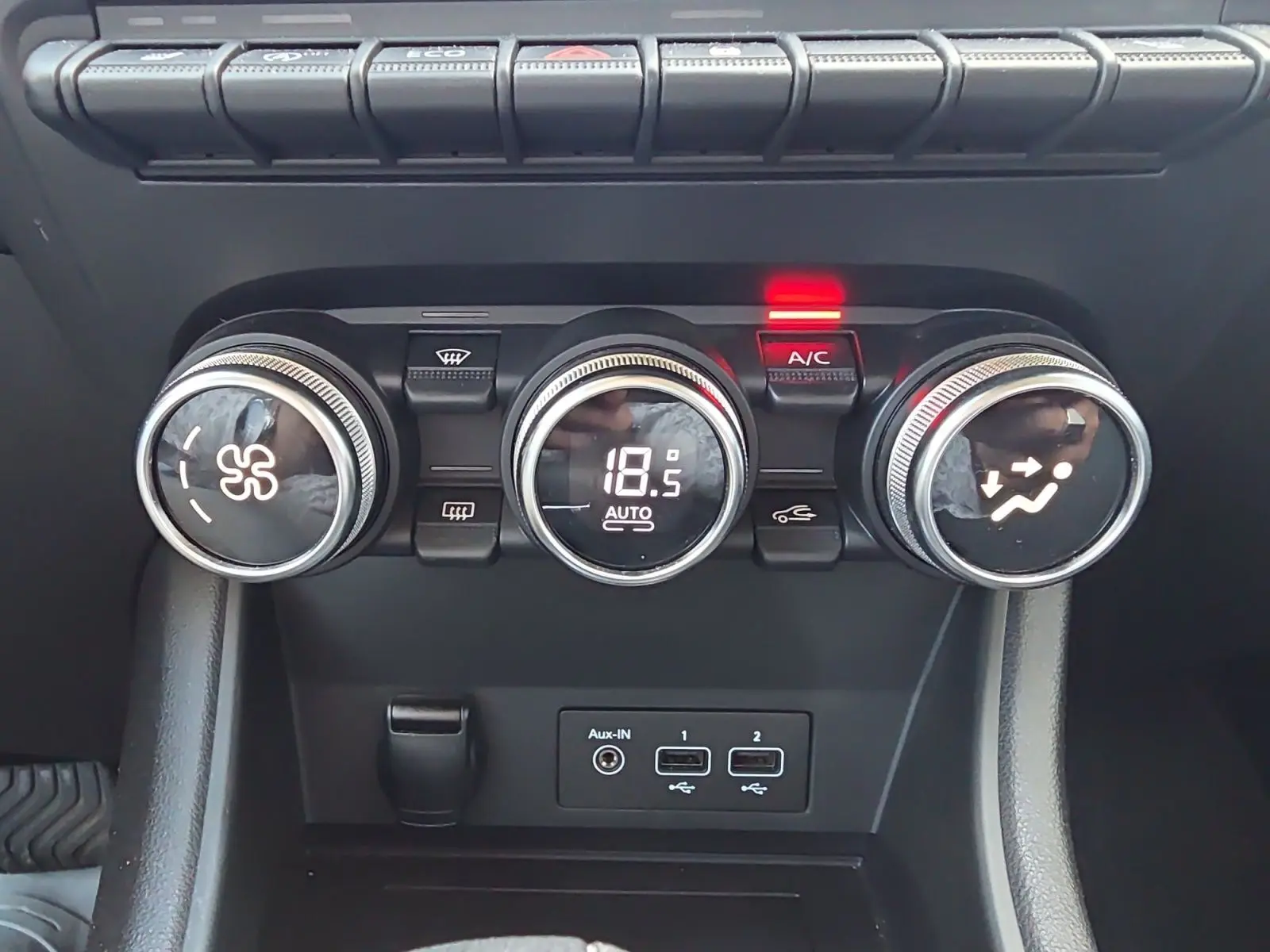 Gros plan sur les commandes de climatisation automatique du Renault Captur noir, avec affichage digital à 18,5°C.