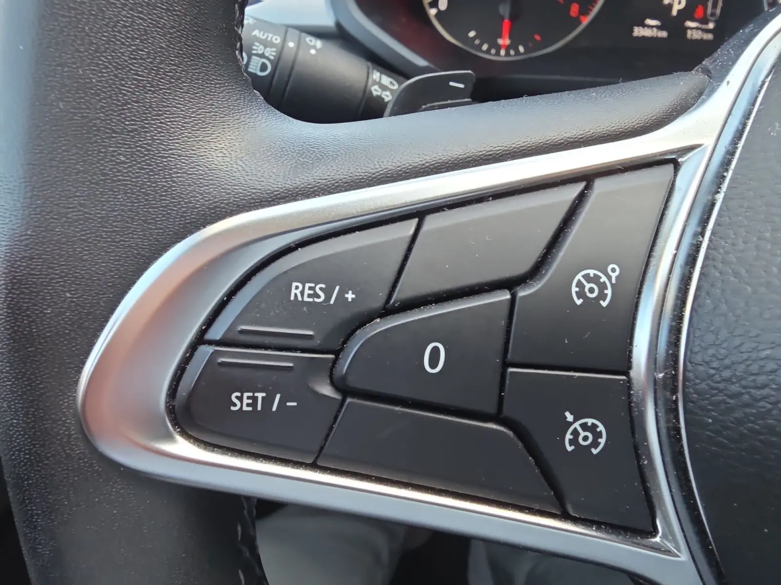 Gros plan sur les commandes du régulateur de vitesse au volant noir du Renault Captur 2021.
