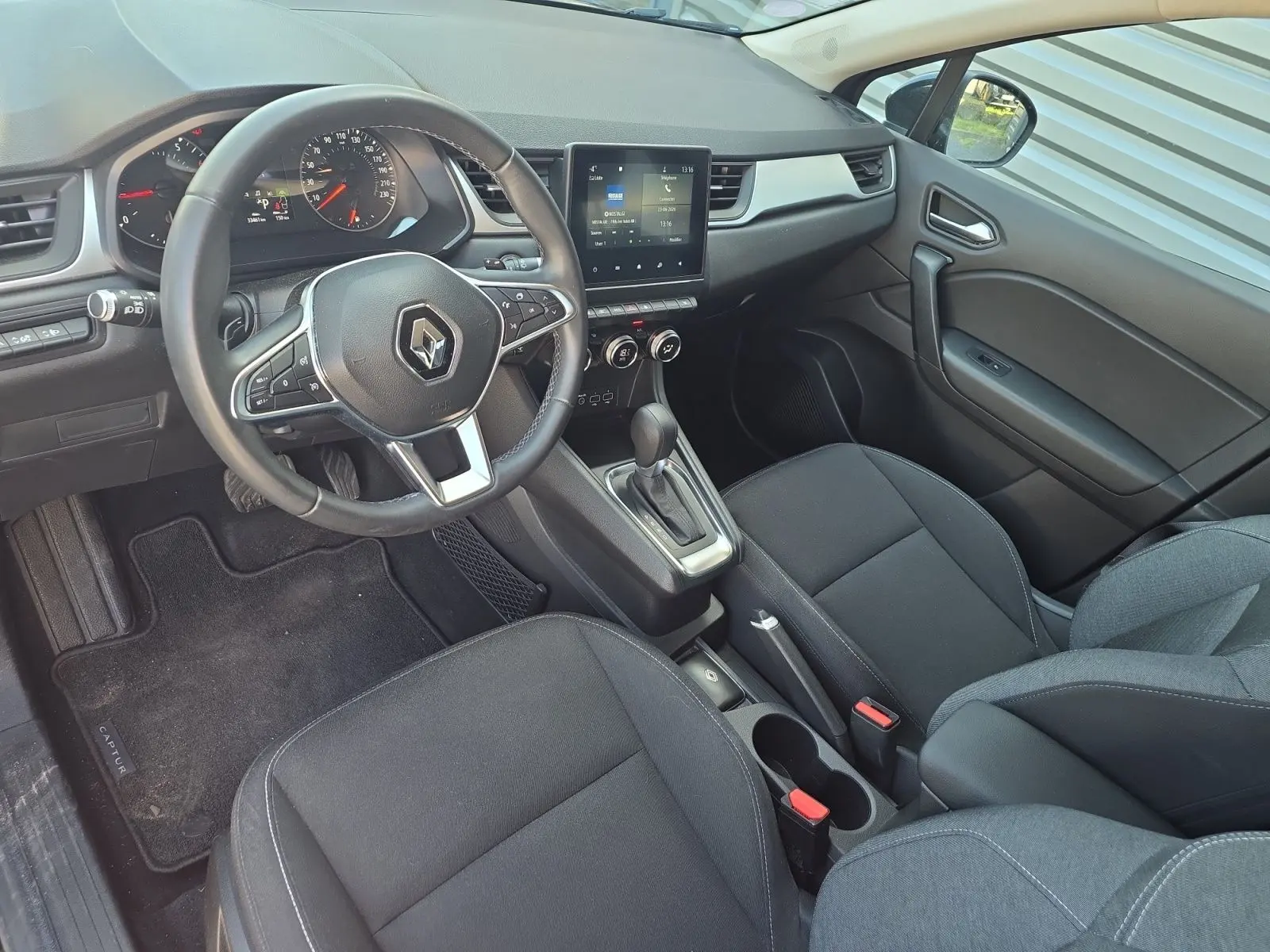 Intérieur noir de Renault Captur 2021 vu côté conducteur, avec volant multifonction et écran tactile central.