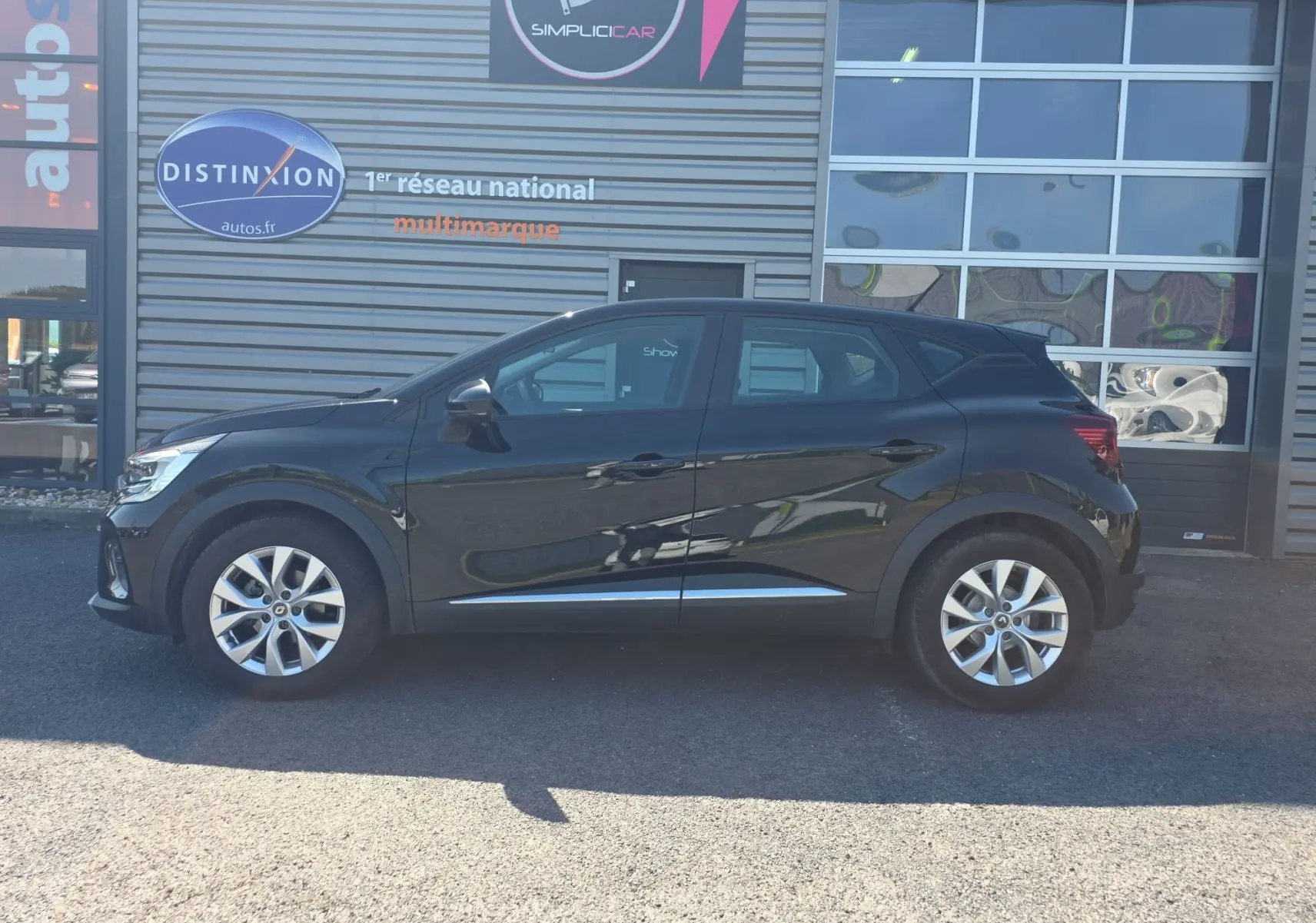 Profil côté gauche d’un Renault Captur noir 2021 avec jantes alliage 17 pouces, garé devant un bâtiment commercial.