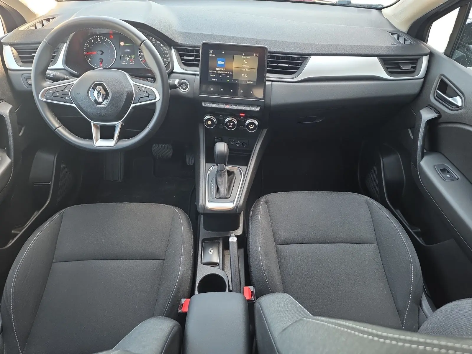 Vue intérieure avant du Renault Captur noir 2021, montrant le tableau de bord, volant multifonction et console centrale avec écran tactile.