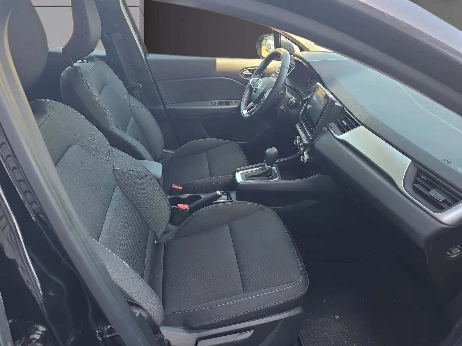 Vue intérieure côté gauche du Renault Captur 2021 noir, montrant sièges avant, volant et console centrale avec boîte auto.