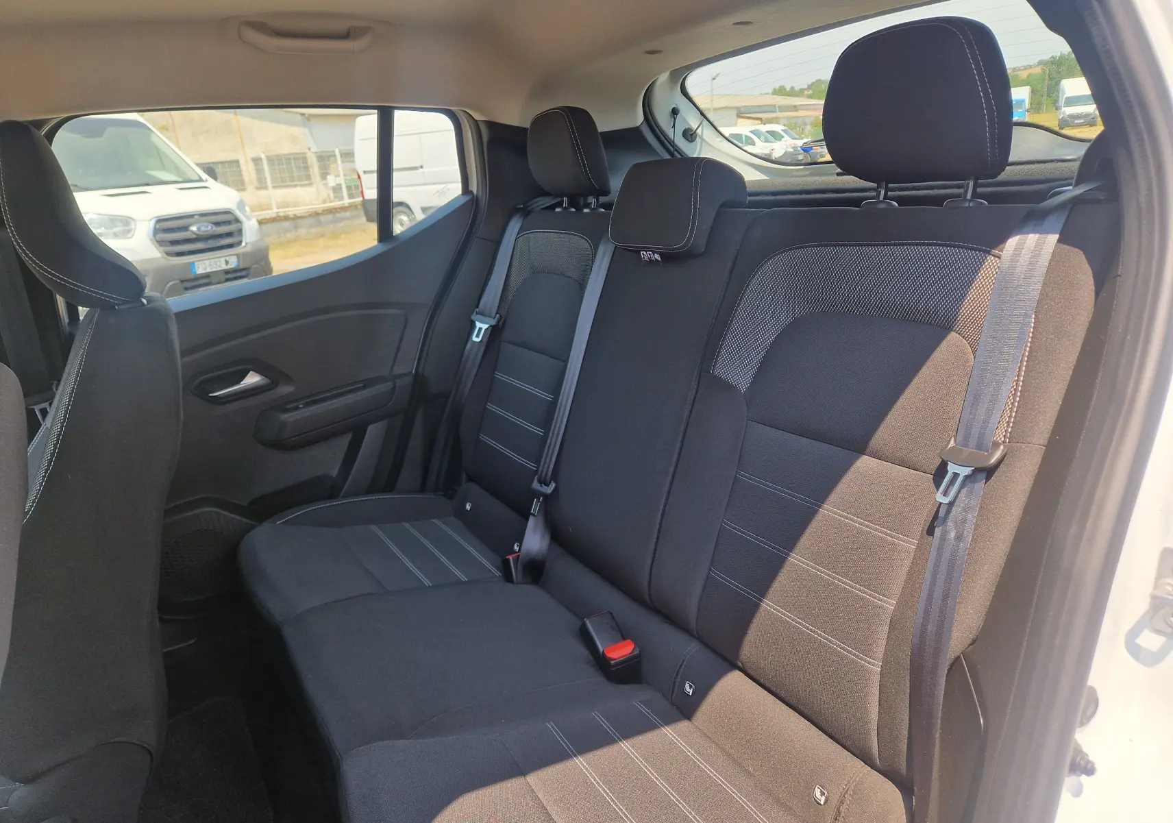 Vue intérieure arrière côté droit montrant les sièges noirs avec ceinture de sécurité d'une Dacia Sandero blanche 2022.
