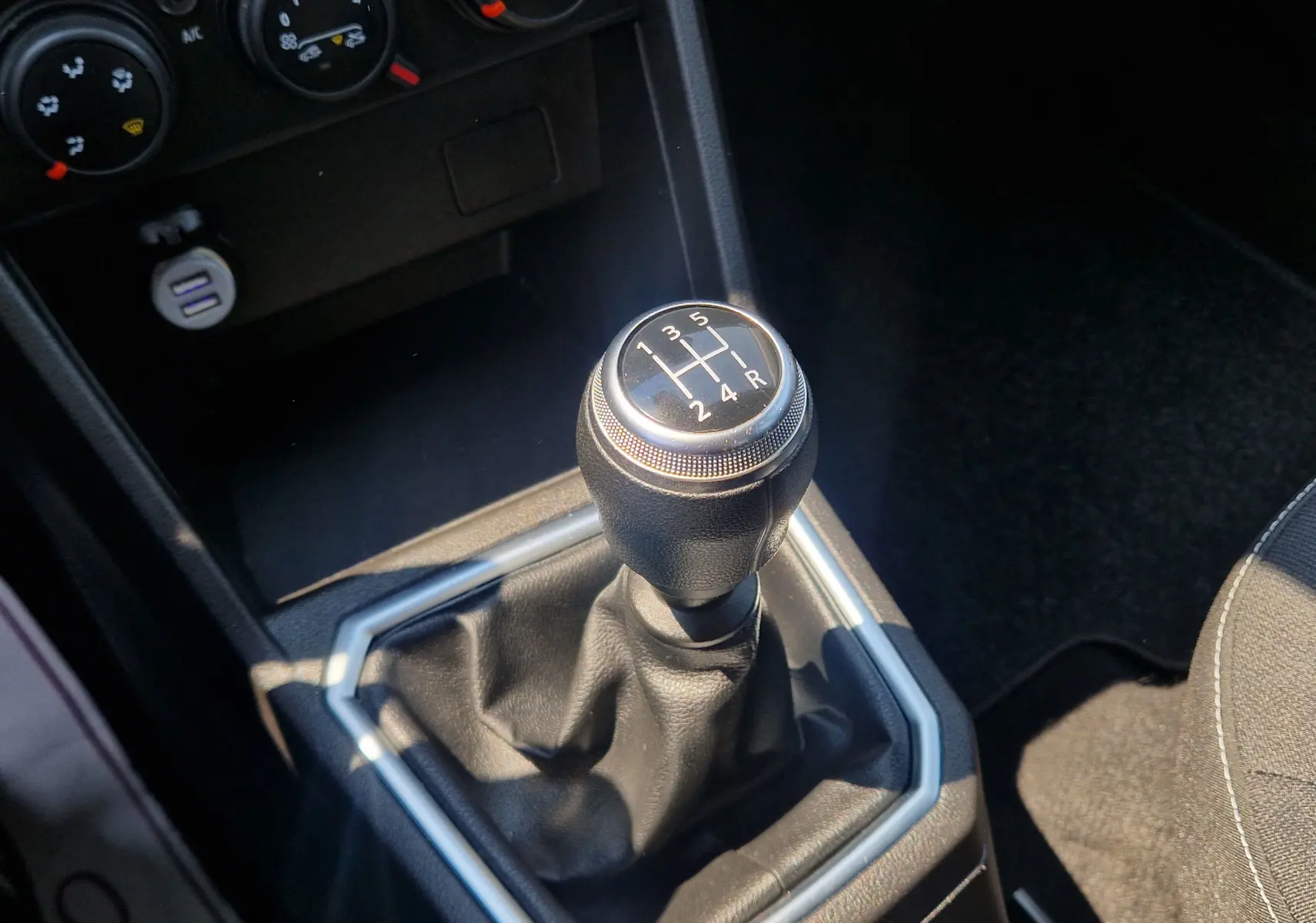 Le levier de vitesses manuel noir de la Dacia Sandero SCE 65 22 Confort, vu en gros plan intérieur.