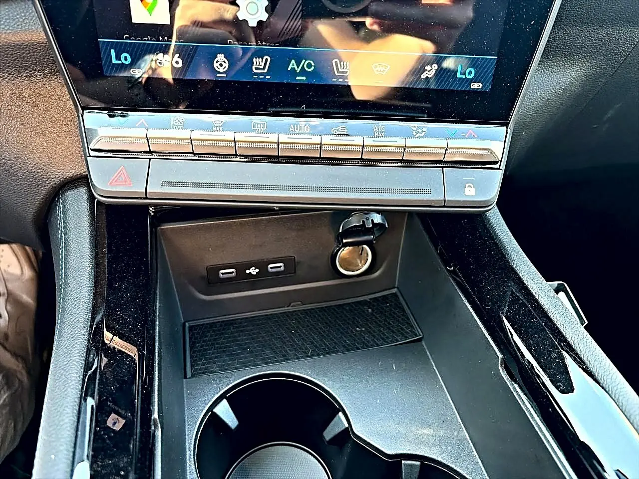Gros plan sur la console centrale noire du Renault Austral 1.2 e-tech, montrant ports USB-C et prise 12V sous l'écran tactile.