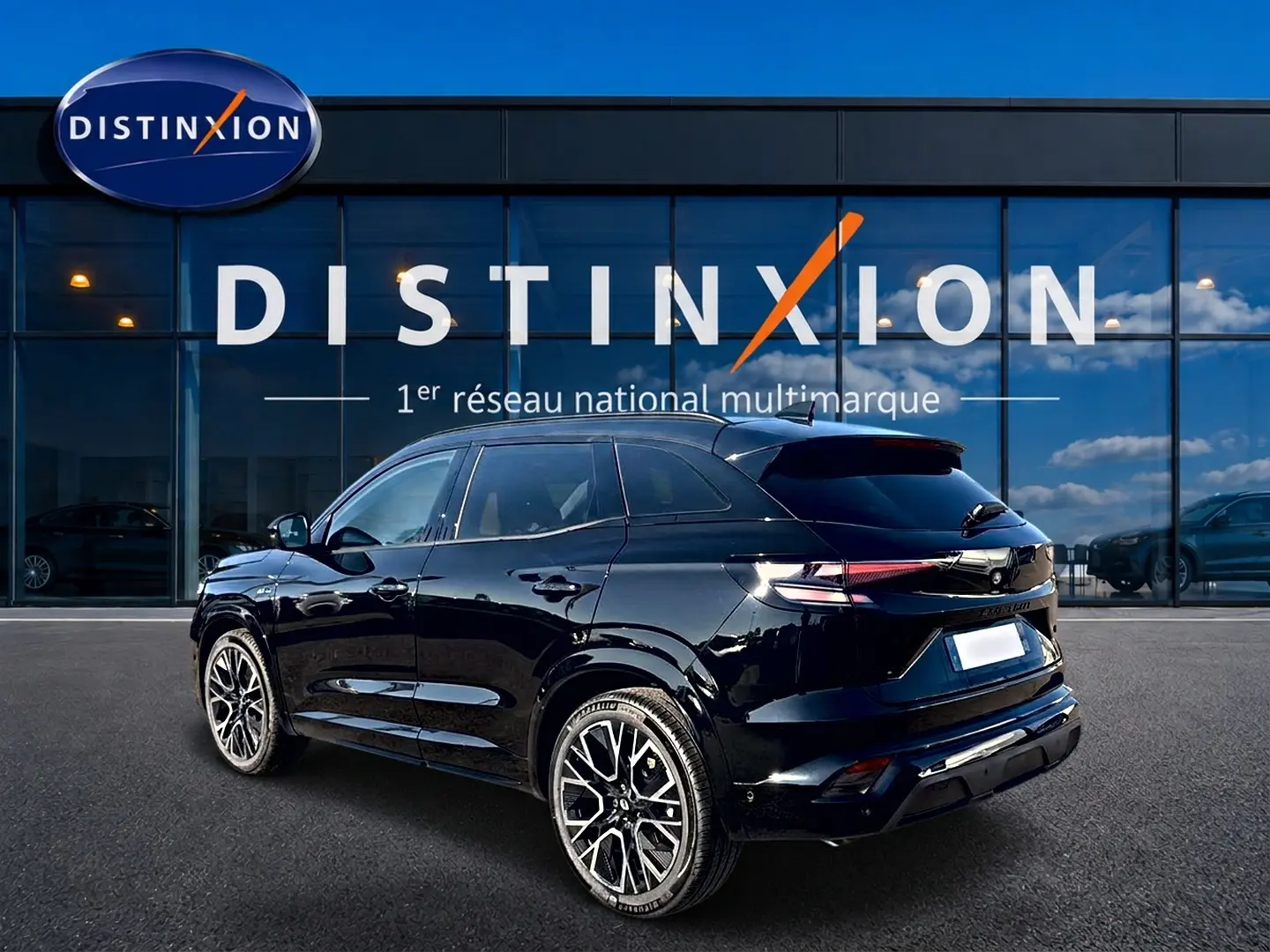 Renault Austral noir en 3/4 arrière droit, jantes alu distinctives, stationné devant une vitrine Distinxion.
