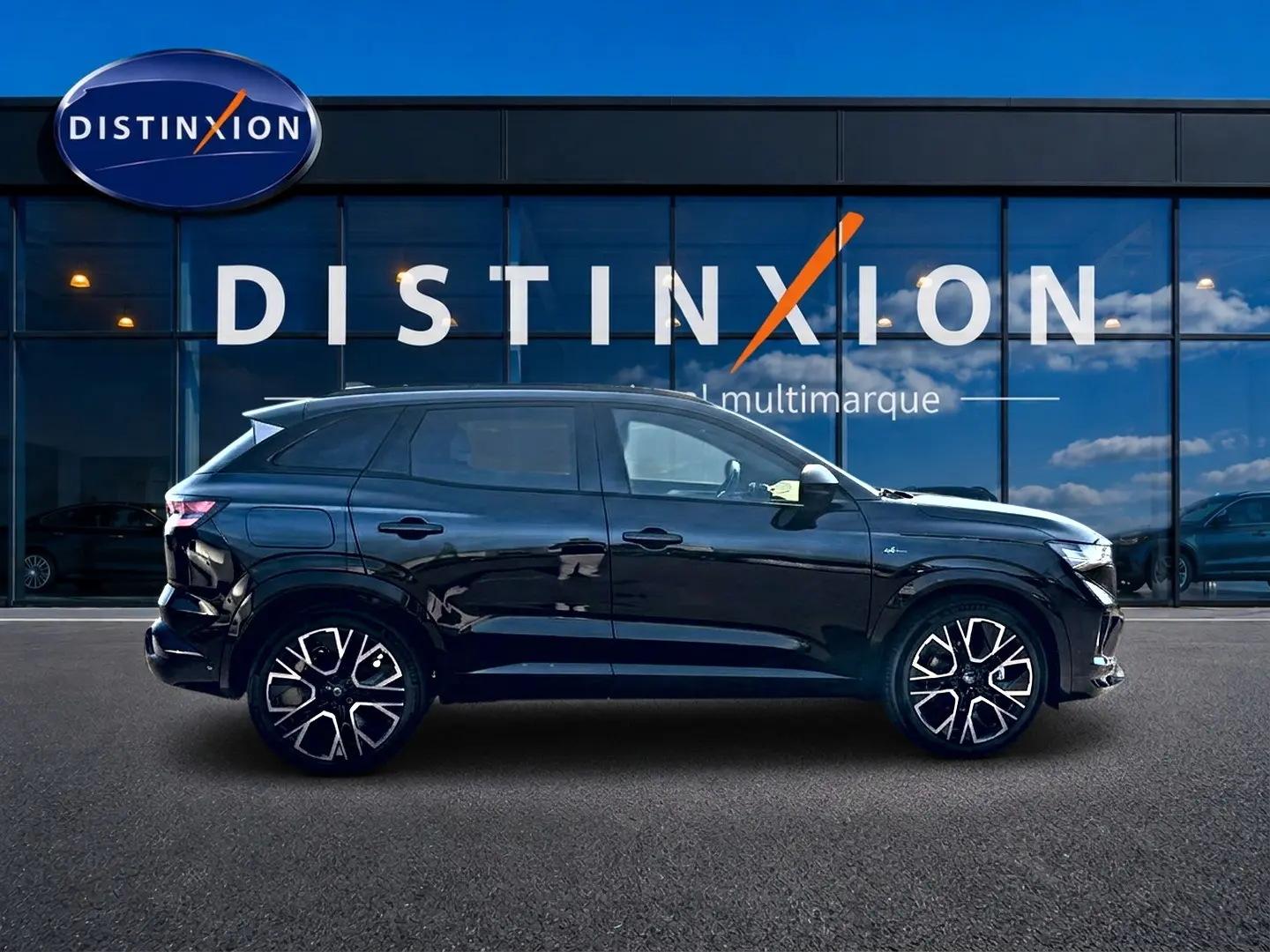 Profil latéral gauche d’un Renault Austral noir brillant avec jantes alu et toit surélevé devant une vitrine Distinxion.