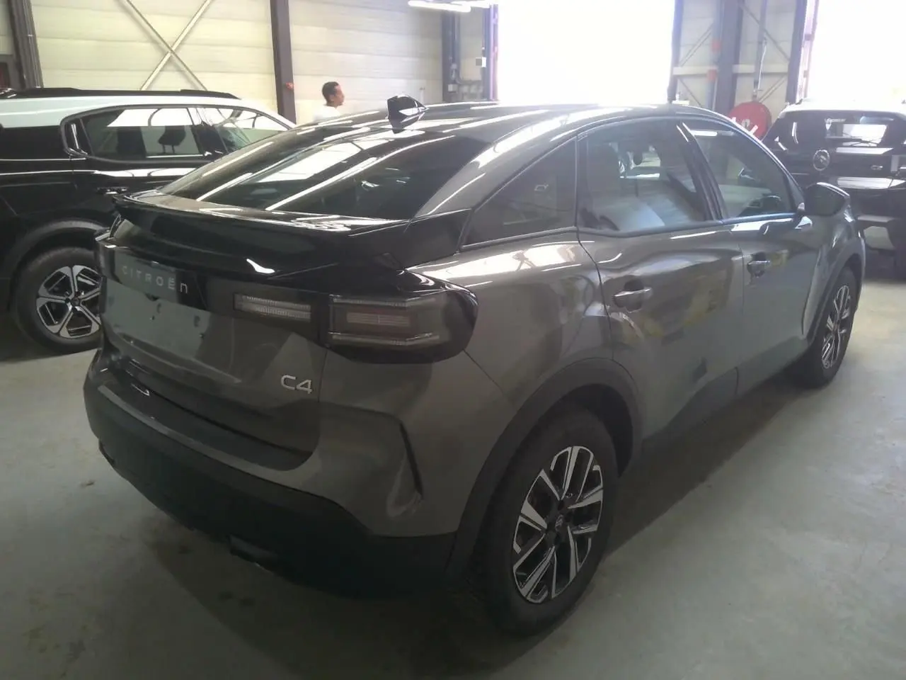 Vue 3/4 arrière droite d'une Citroën C4 hybride gris Mercury avec jantes bi-ton et feux arrière LED.