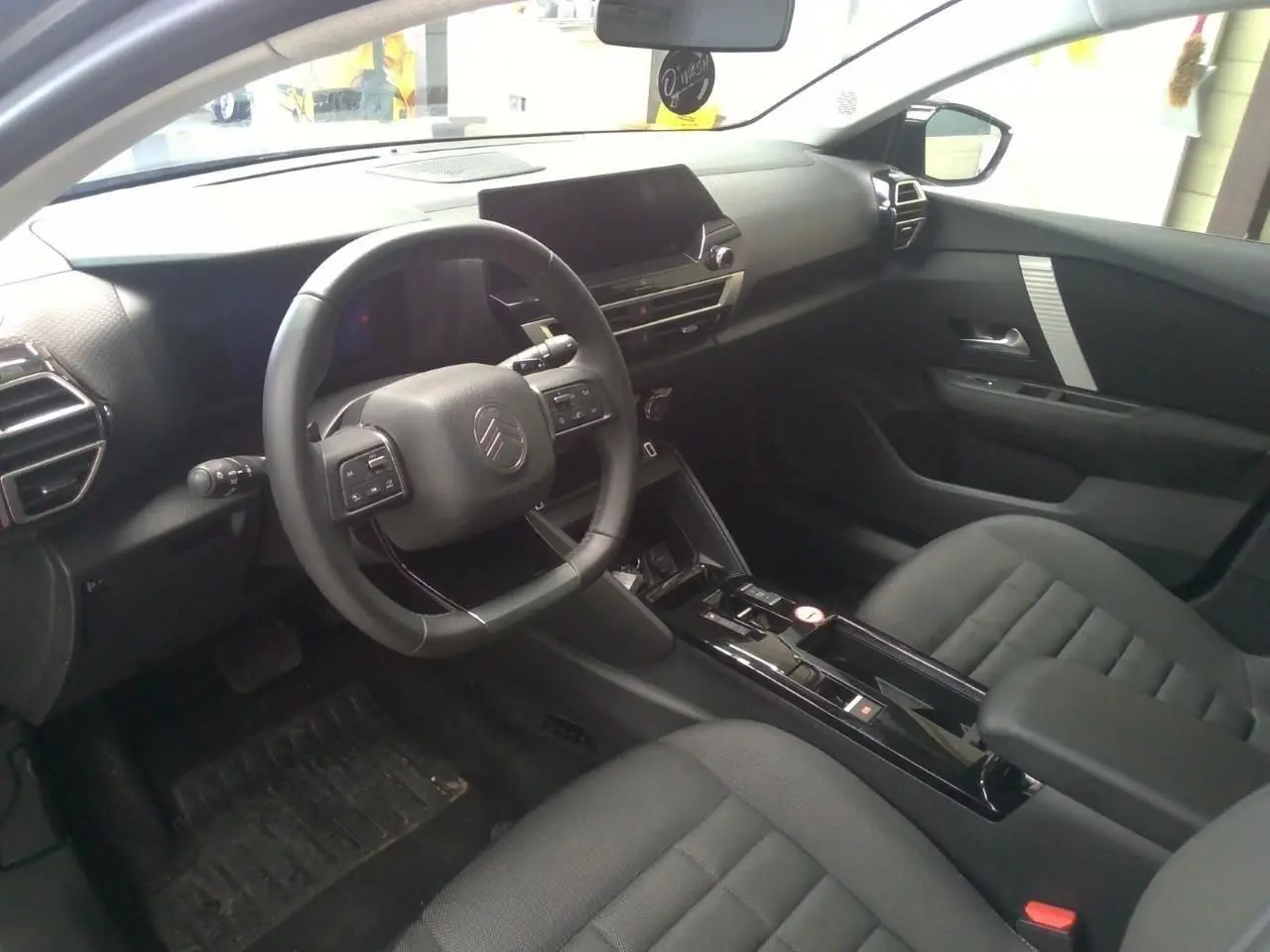 Intérieur avant droit de la Citroën C4 hybride 2025, tableau de bord moderne avec écran tactile et volant multifonction noir.