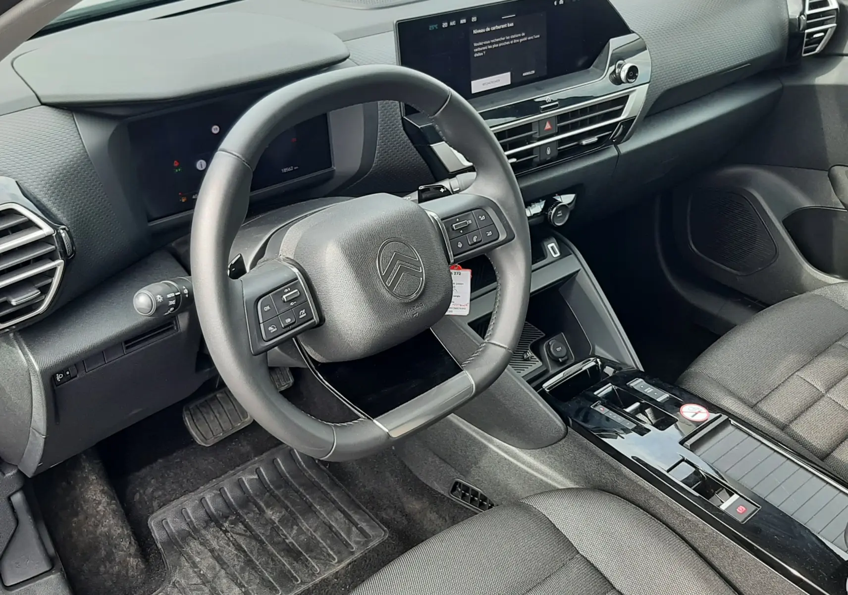 Intérieur avant du Citroën C4 Hybrid 2025, vue côté conducteur, tableau de bord gris noir avec écran tactile central.