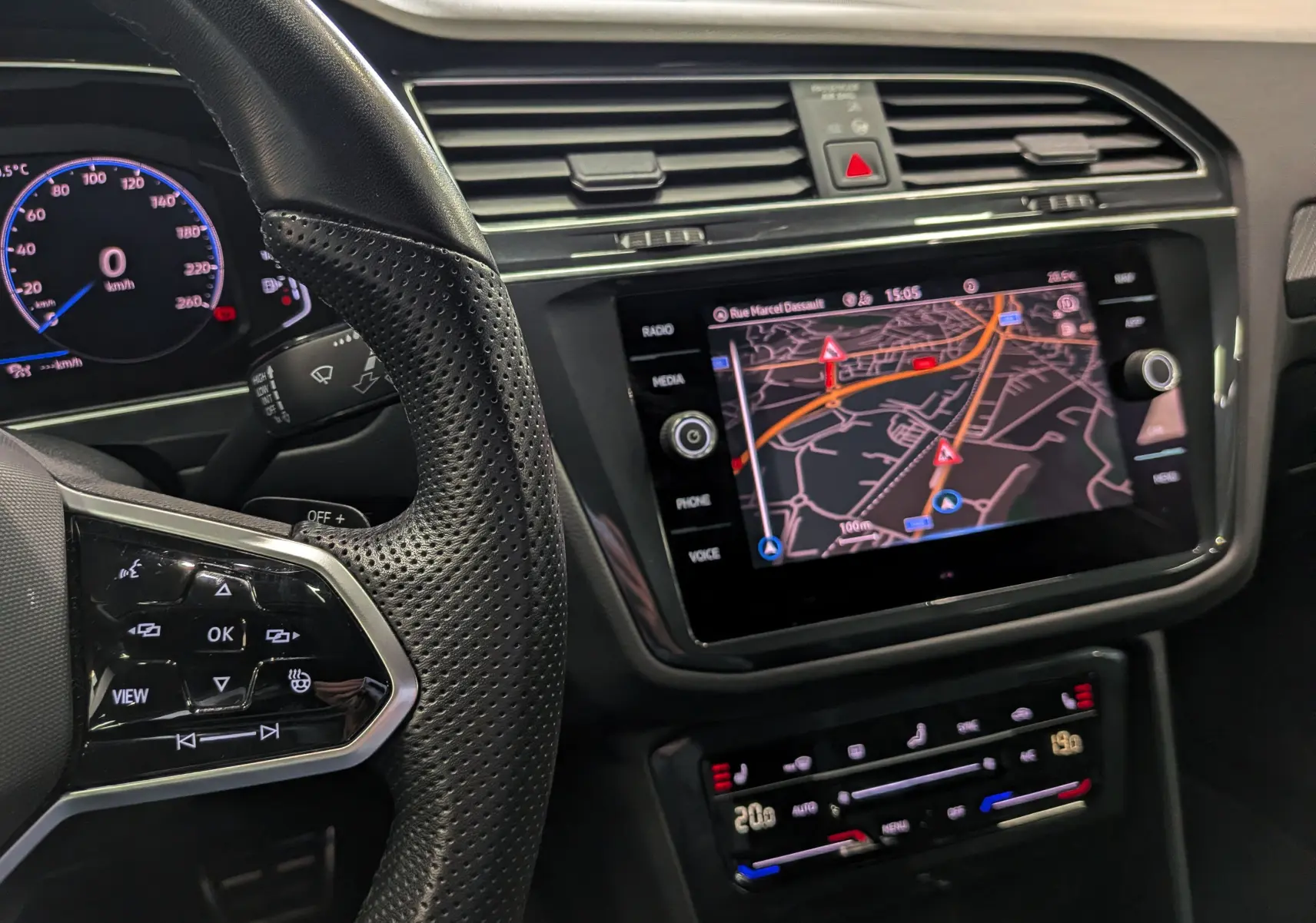 Vue rapprochée de l’intérieur du Volkswagen Tiguan 2024, volant perforé noir et écran tactile avec navigation affichée.