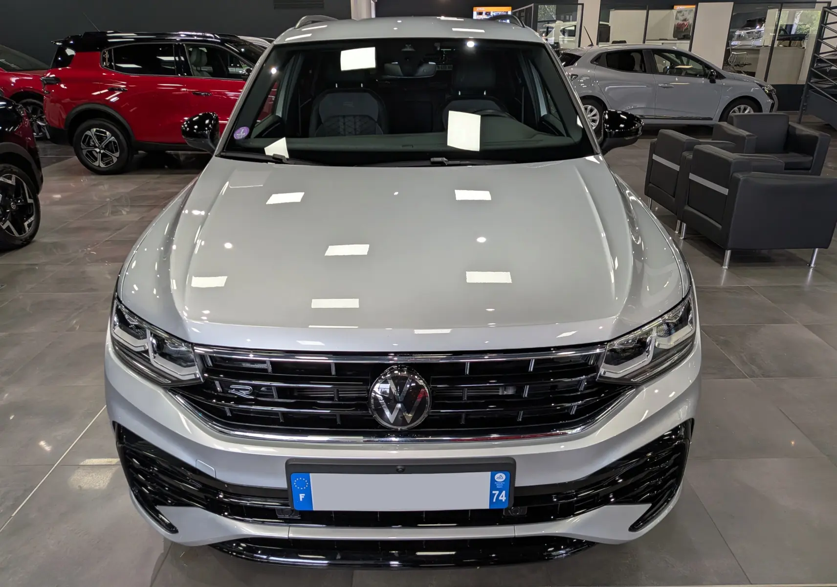 Vue avant d’un Volkswagen Tiguan 1.5 TSI R-Line 2024 en reflet d’argent, avec calandre noire et logo VW central.