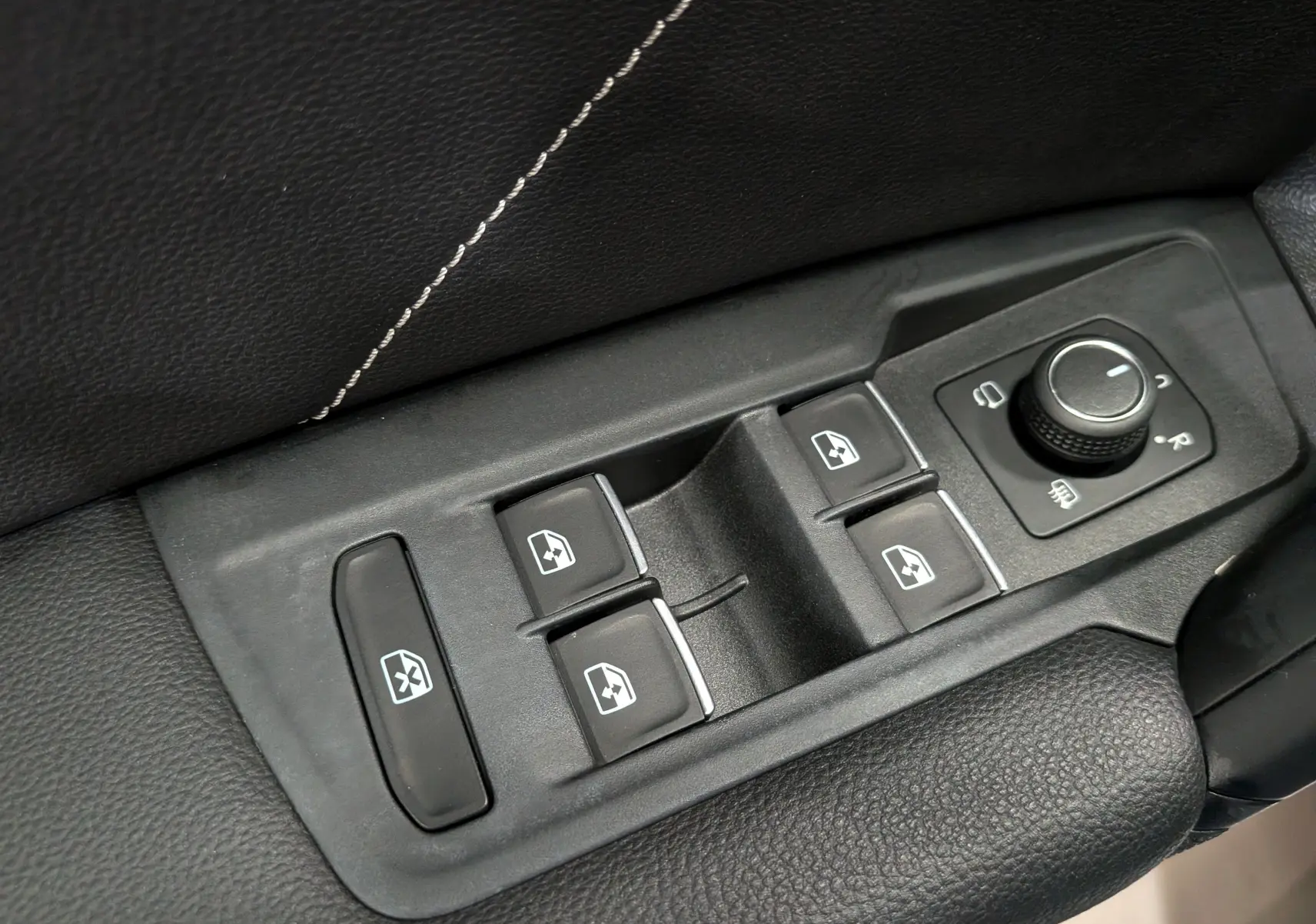 Gros plan sur les commandes de lève-vitres et réglage des rétroviseurs du Volkswagen Tiguan 2024 finition R-Line.