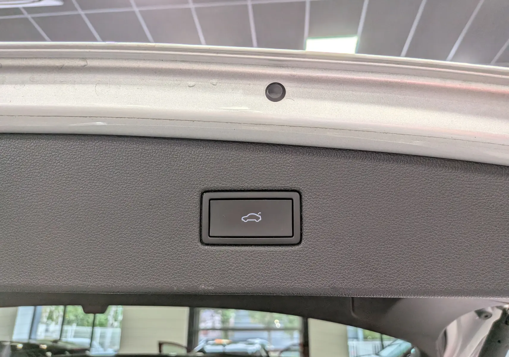 Bouton d'ouverture électrique du coffre sur la partie intérieure du hayon du Volkswagen Tiguan reflet d'argent 2024.