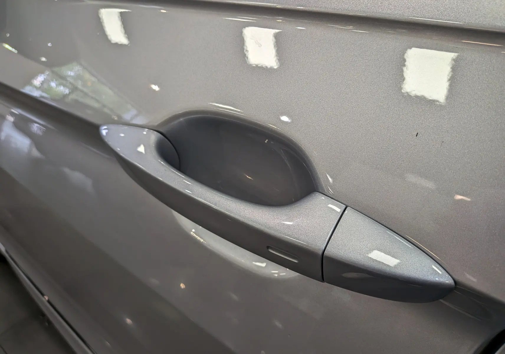 Poignée de porte côté gauche en gros plan sur Volkswagen Tiguan 2024 reflet d'argent avec finition lisse et capteur intégré.