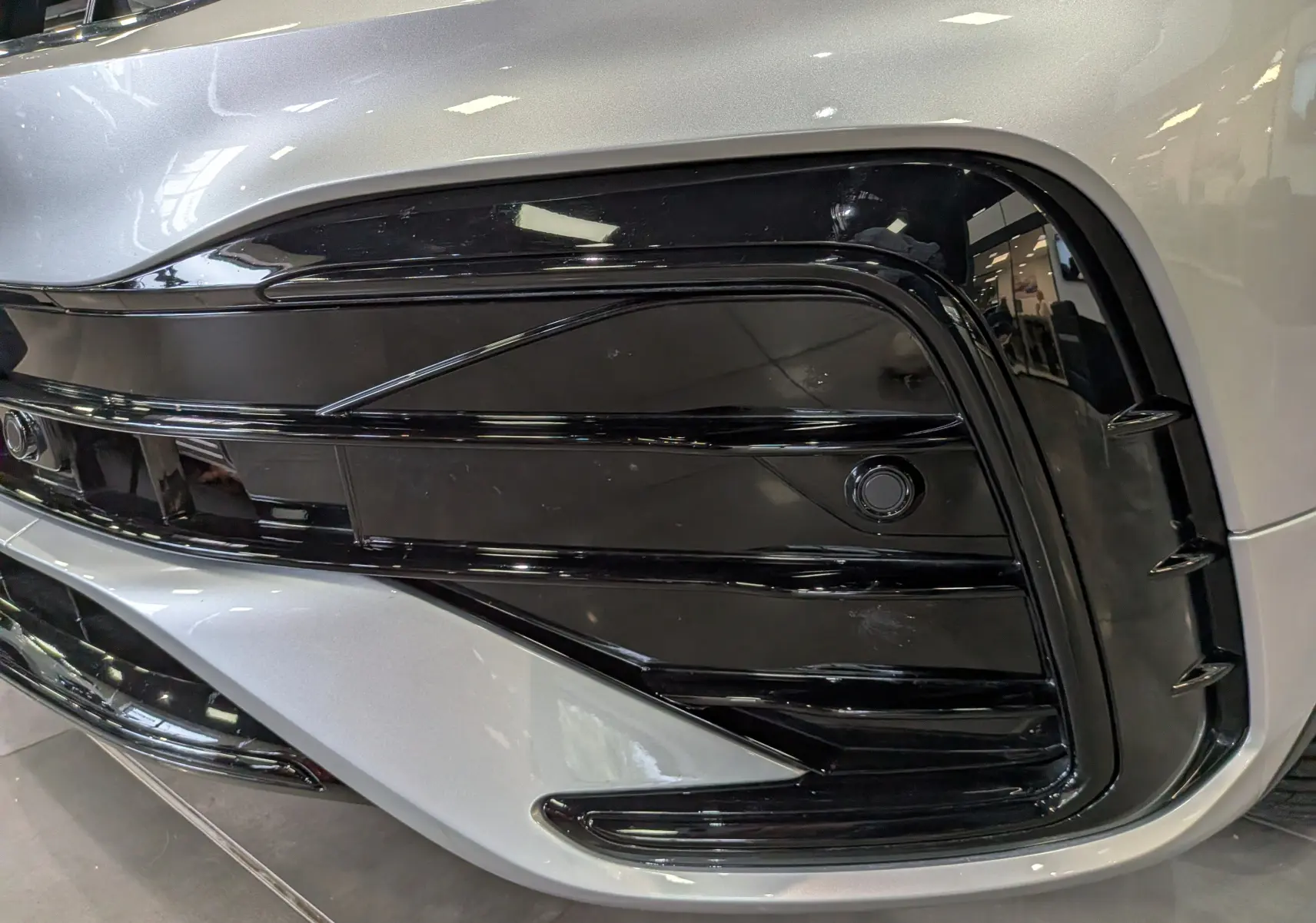 Gros plan sur la partie avant droite du Volkswagen Tiguan 2024 reflet d'argent, mettant en valeur la calandre noire brillante.