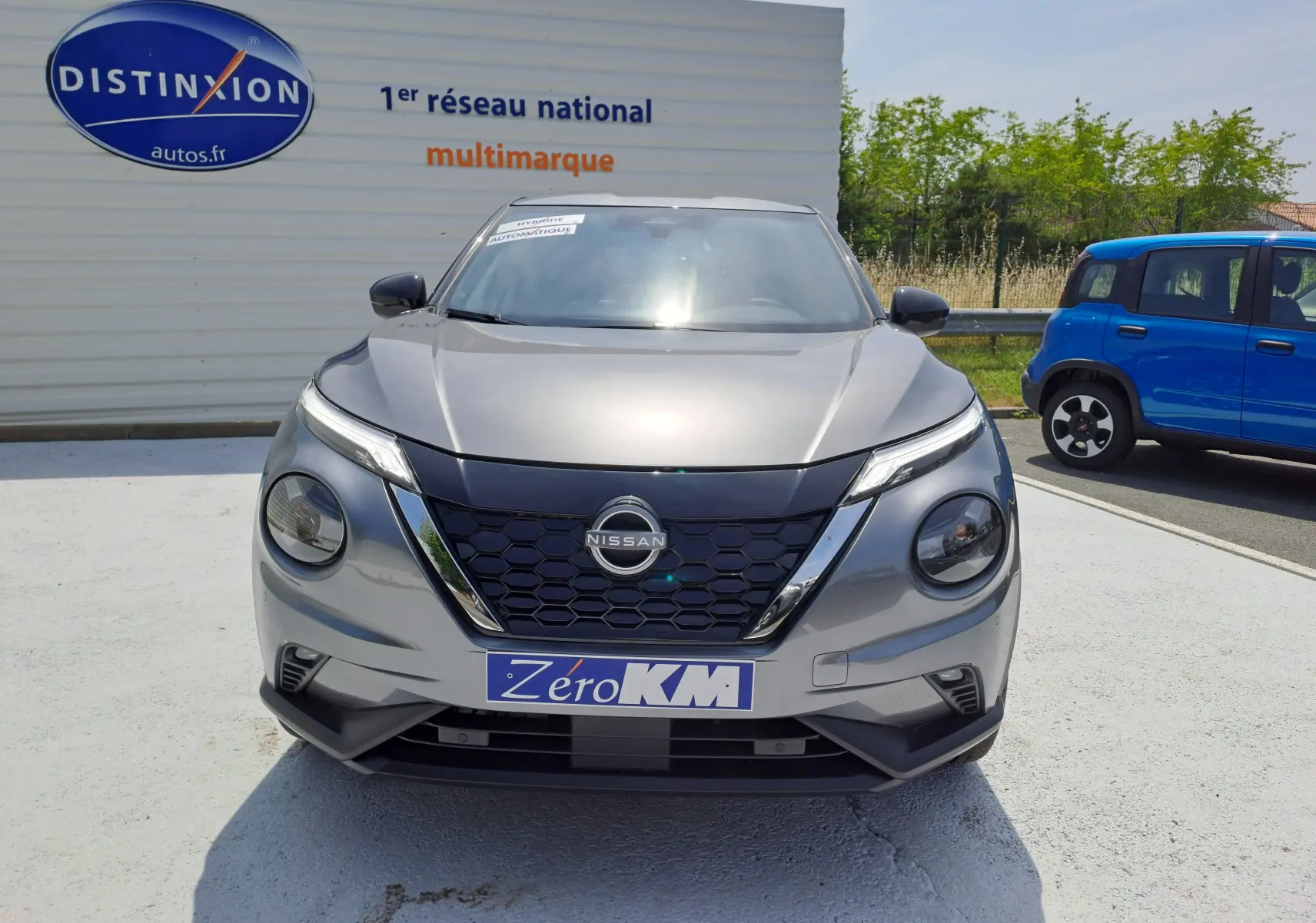 Vue de face du Nissan Juke Hybrid 143 N-Connecta gris squale avec calandre noire et phares ronds distinctifs.