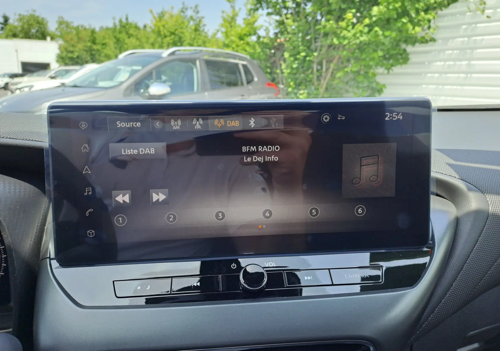 Écran tactile central du Nissan Juke Hybrid 2025 affichant la radio DAB BFM Radio en extérieur lumineux.