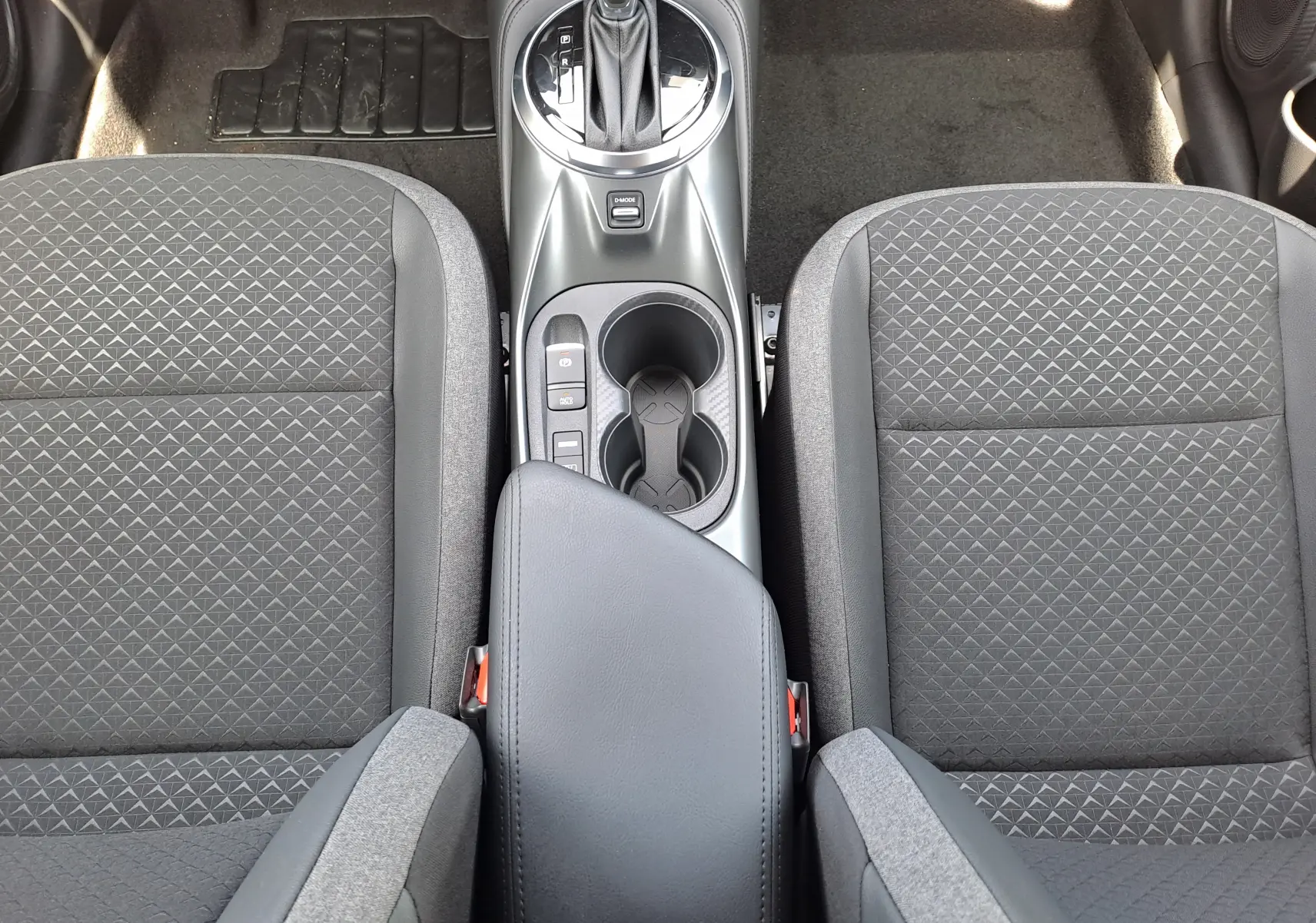 Vue plongeante sur la console centrale et les sièges avant en tissu gris du Nissan Juke Hybrid 143 N-Connecta 2025.