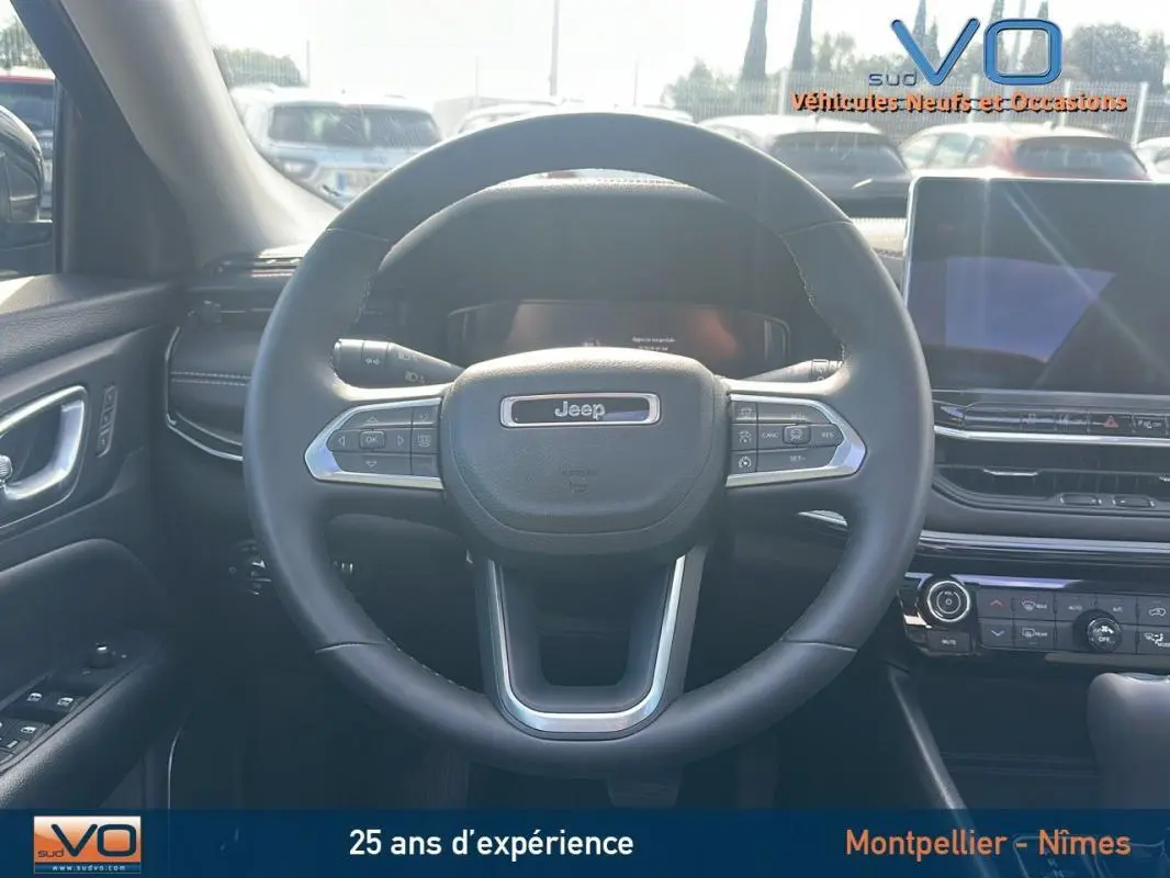 Vue centrée sur le volant cuir du Jeep Compass 2023 avec tableau de bord et écran tactile en arrière-plan.