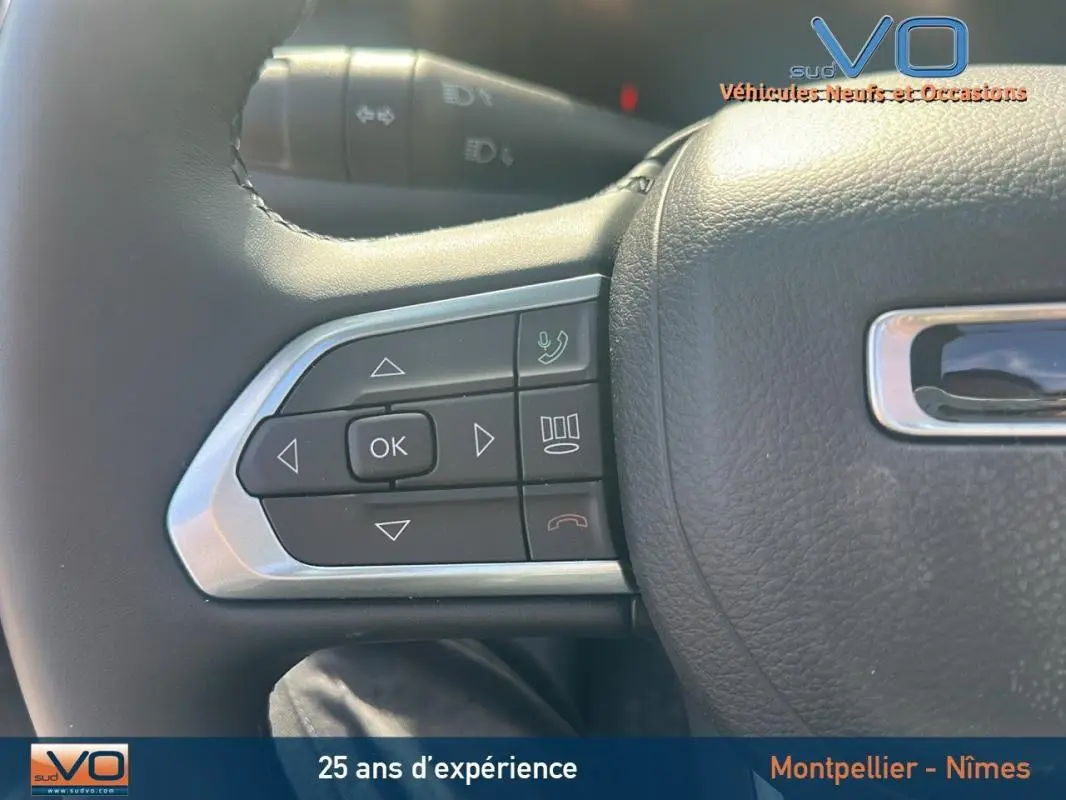 Gros plan sur les commandes gauche du volant cuir du Jeep Compass noir 2023, avec boutons de navigation et appel.