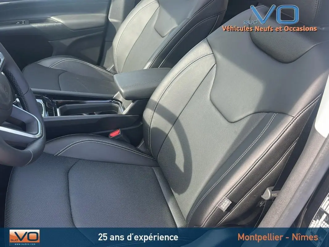 Intérieur noir du Jeep Compass 2023, vue côté conducteur sur sièges cuir avec accoudoir central et volant partiel visible.