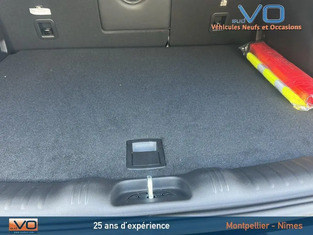 Coffre spacieux et propre du Jeep Compass noir 2023, avec tapis de sol et triangle de signalisation visible à droite.