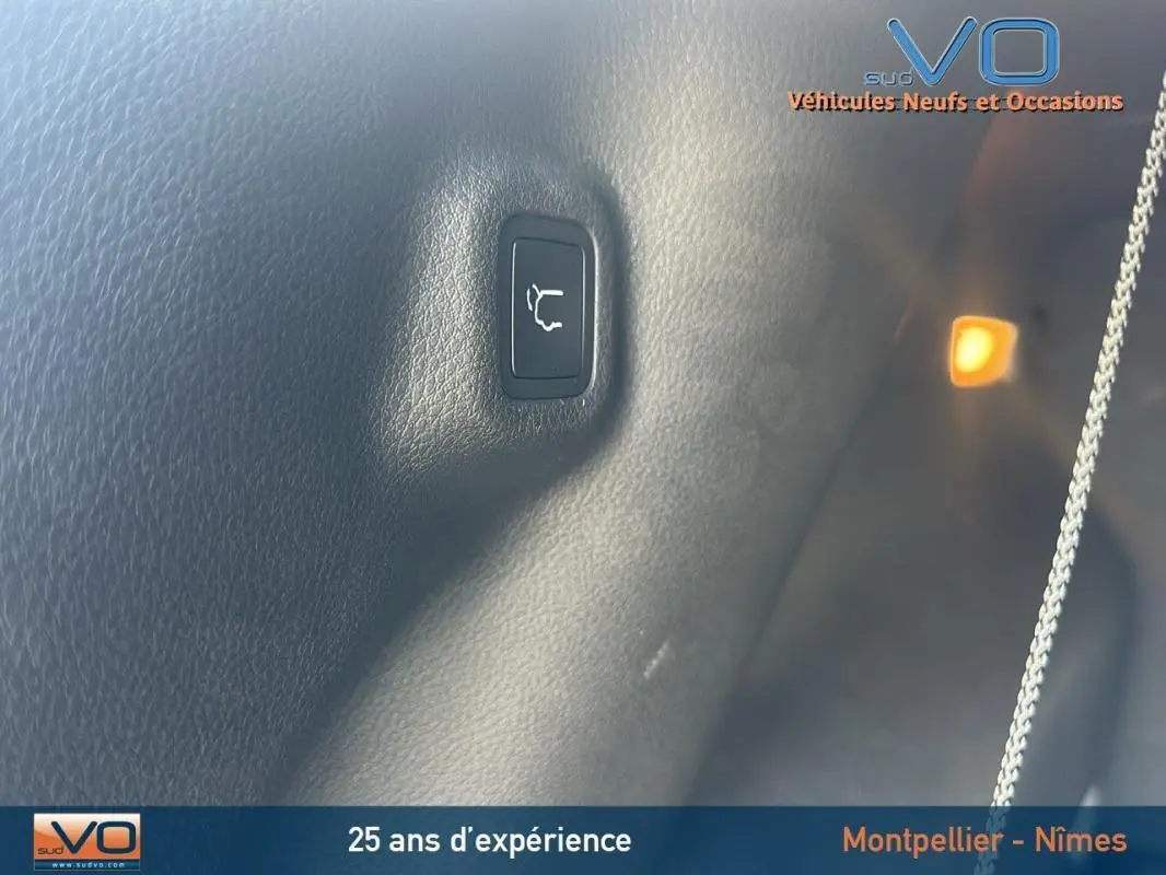 Gros plan sur le bouton d'ouverture du coffre dans l'habitacle noir du Jeep Compass 2023 e-Hybrid.