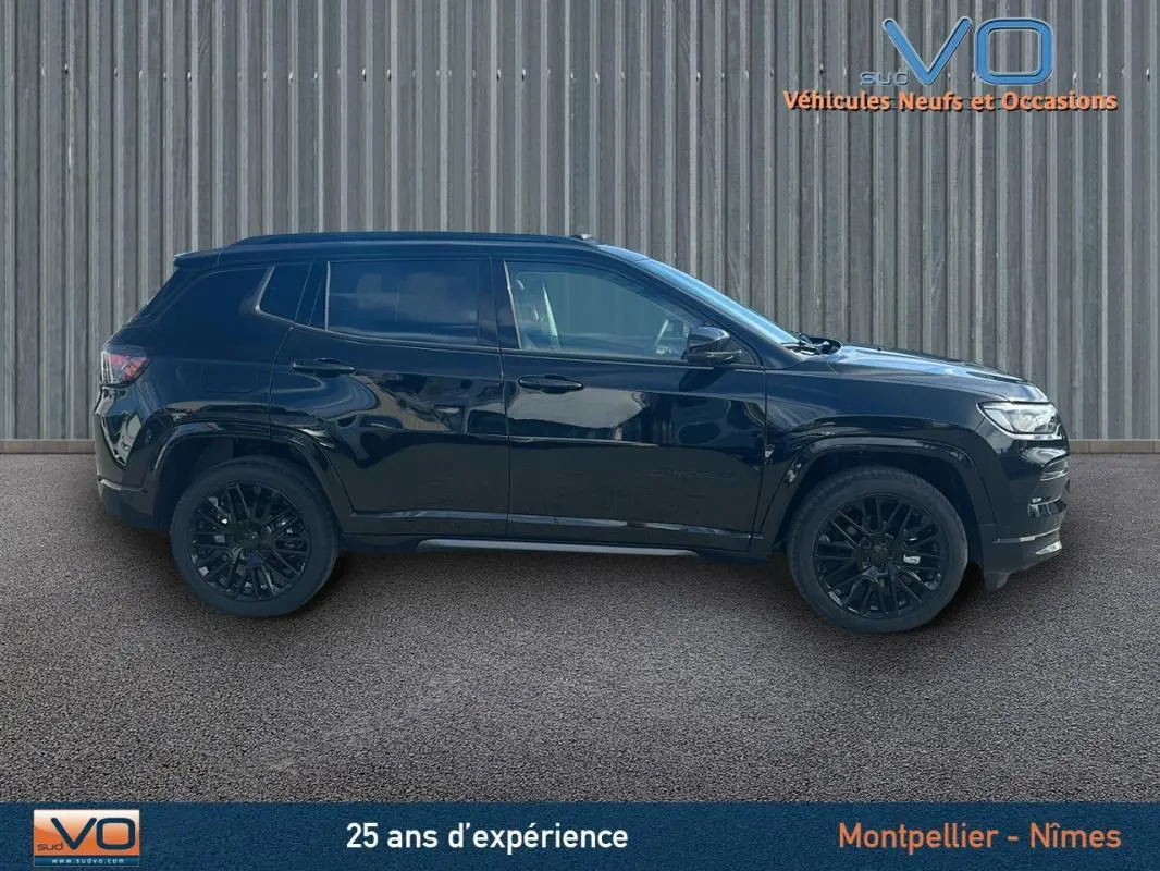 Profil côté gauche du Jeep Compass noir 2023 avec jantes alliage noires et barres de toit visibles.