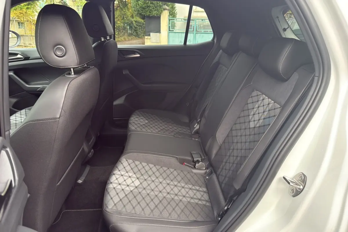 Vue latérale droite de l'intérieur arrière du Volkswagen T-Cross blanc avec sièges tissu à motif géométrique.