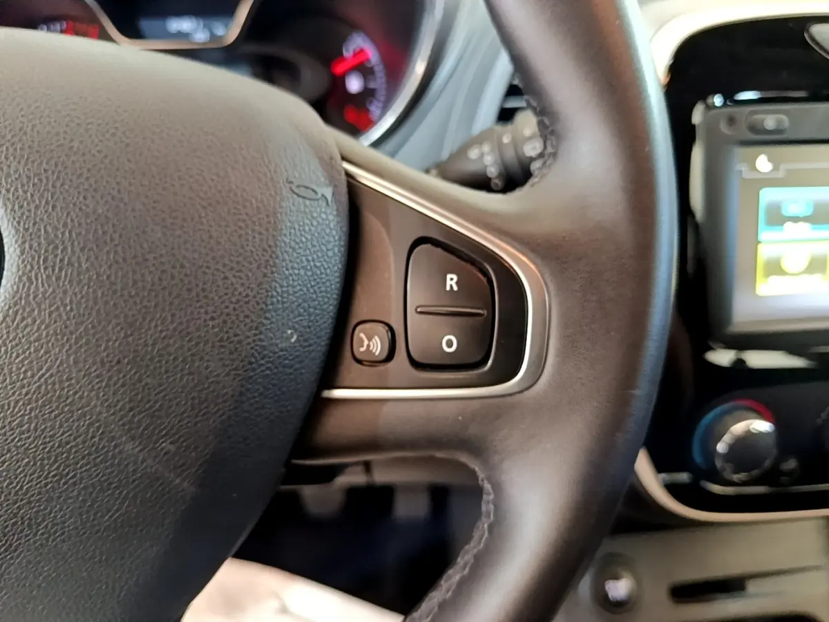 Gros plan sur le volant cuir noir du Renault Captur Business 2018 avec commandes vocales et écran tactile partiel en arrière-plan.