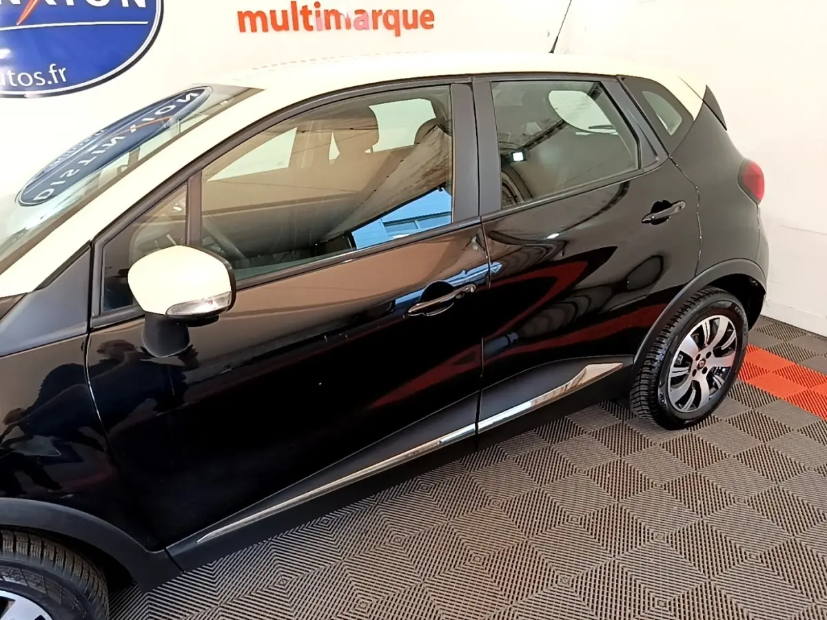 Profil côté gauche du Renault Captur noir avec rétroviseur blanc et jantes alliage visibles en intérieur showroom.