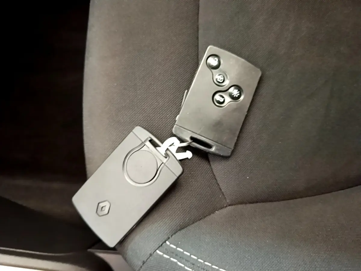 Clé de voiture Renault Captur Business TCe 90 noire posée sur un siège tissu noir à coutures visibles.