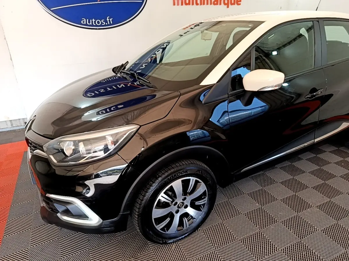 Vue 3/4 avant droit du Renault Captur Business noir avec rétroviseur blanc et jantes alliage bicolores.