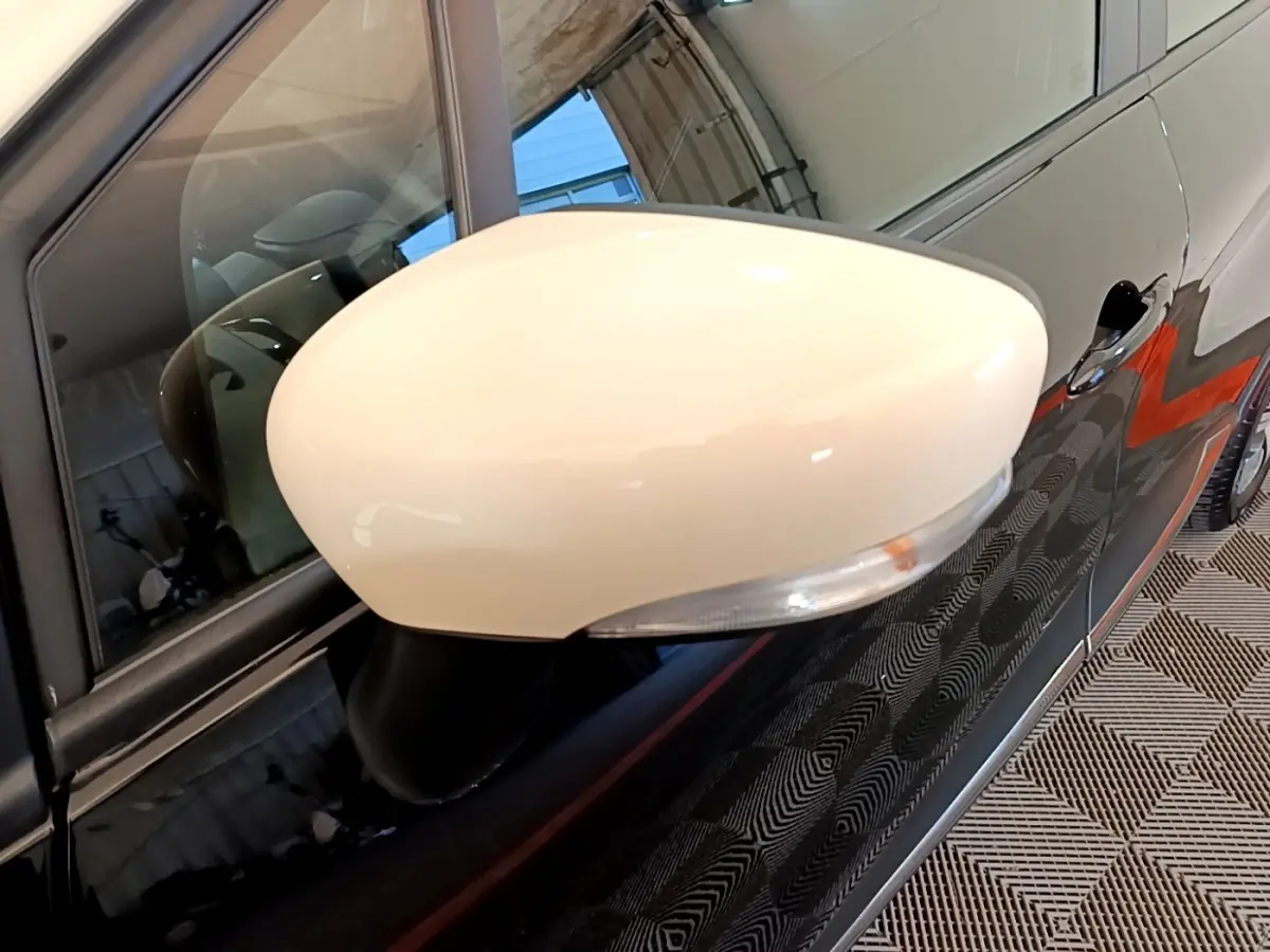 Rétroviseur droit blanc sur Renault Captur noir, vue rapprochée du côté avant droit avec poignée de porte visible.