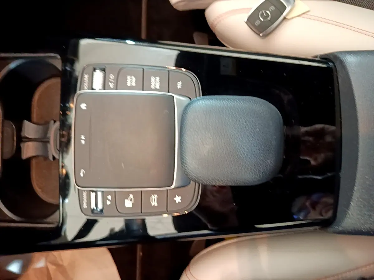 Vue plongeante sur la console centrale noire brillante de la Mercedes Classe A 250 e Business Line avec pavé tactile et pommeau cuir.