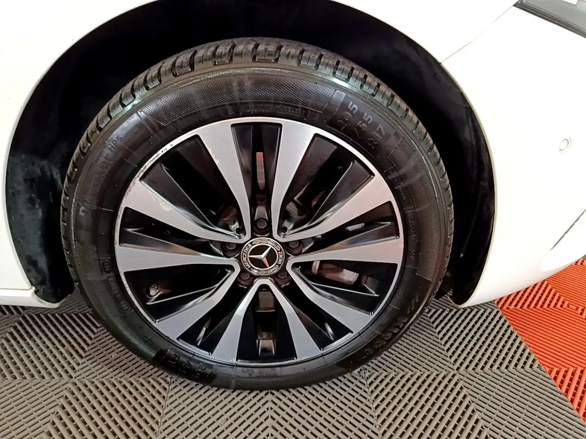 Gros plan sur la roue avant droite d’une Mercedes Classe A blanche, jante alliage bicolore au design moderne.