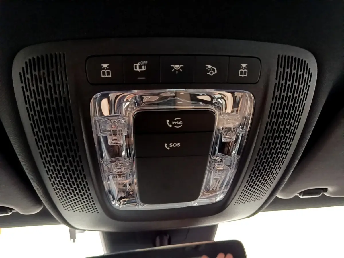 Gros plan sur la console de toit noire avec commandes d’éclairage et boutons SOS d’une Mercedes Classe A blanche.