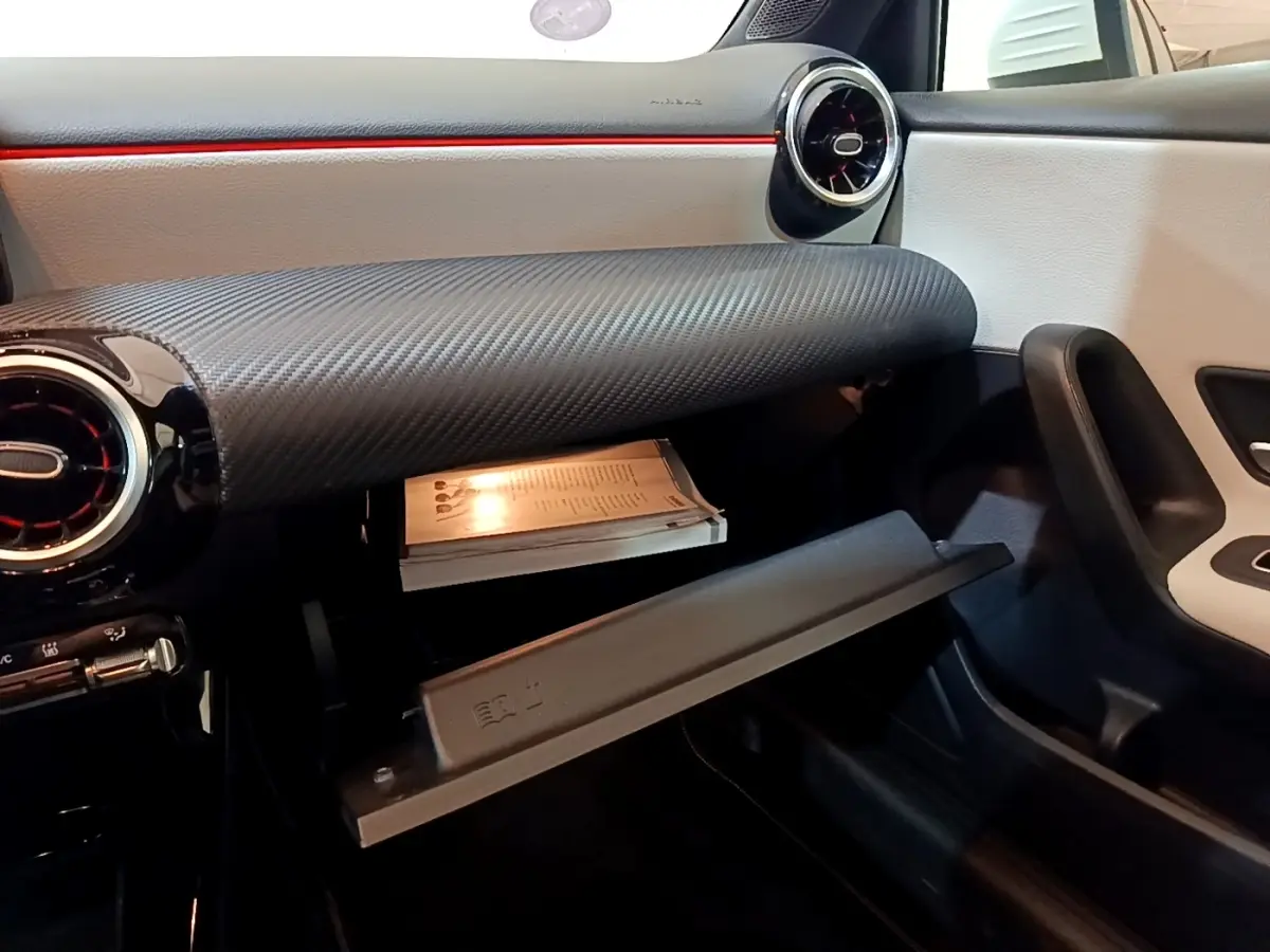 Vue intérieure côté passager de la Mercedes Classe A 250 e Business Line 2020, boîte à gants ouverte et tableau de bord noir et blanc.