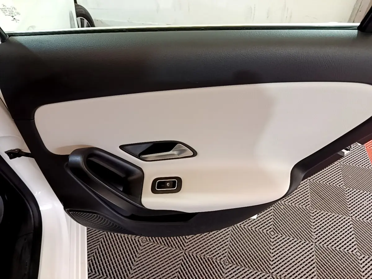 Vue intérieure de la porte avant gauche blanche de la Mercedes Classe A Berline A 250 e avec garniture bicolore noire et beige.