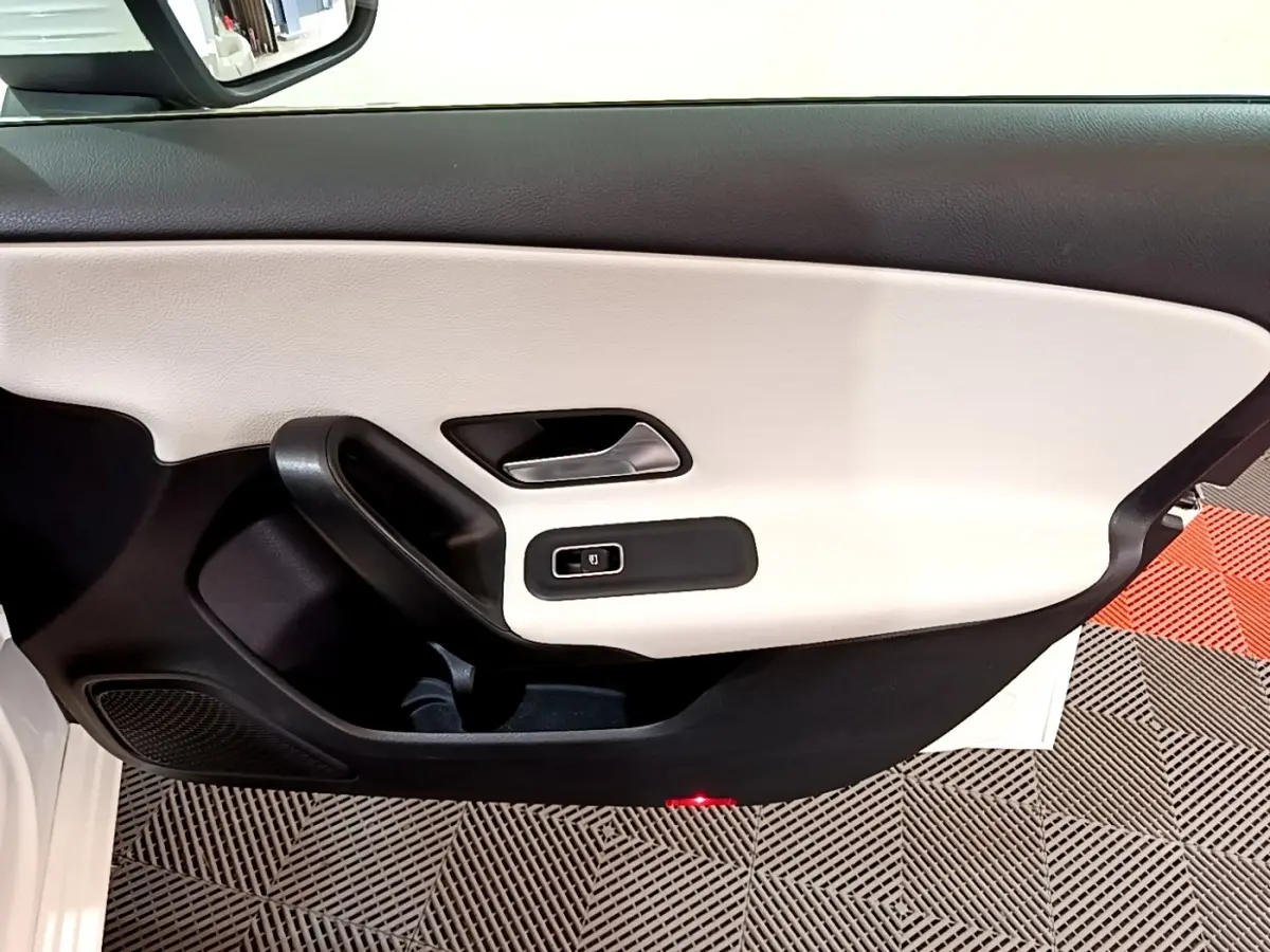 Vue rapprochée de la porte avant gauche blanche de la Mercedes Classe A Berline avec garniture bicolore noir et beige.