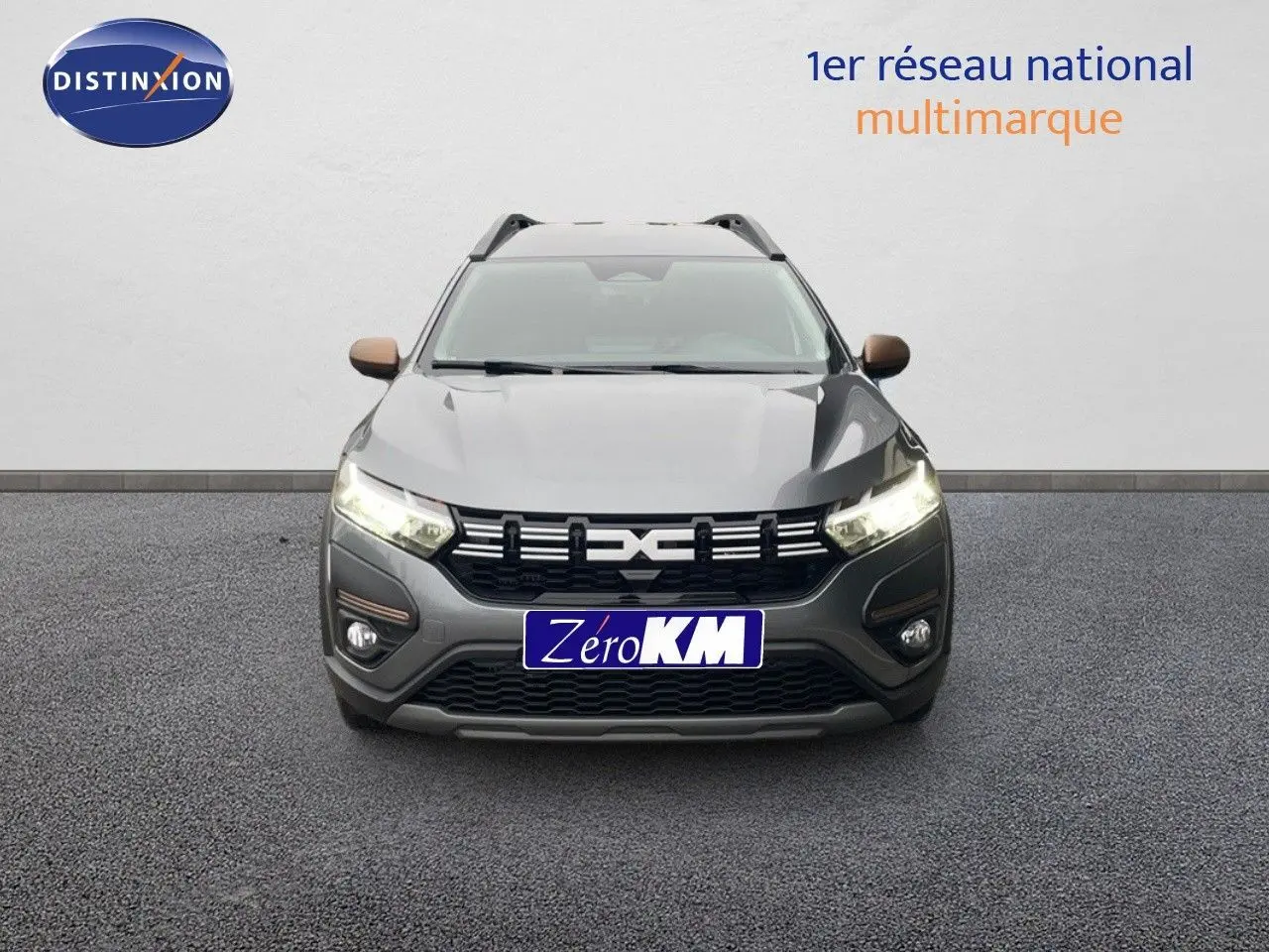 Vue avant d'un Dacia Jogger gris schiste métal 2026 avec calandre noire et feux allumés sur fond neutre.